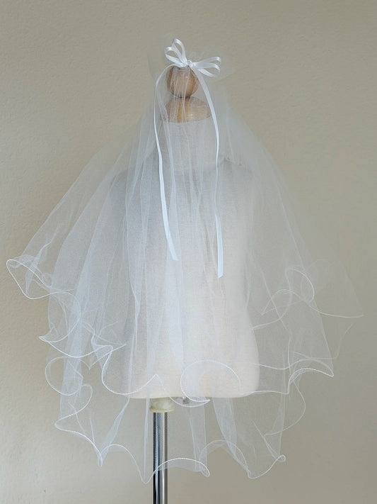 White first communion veil on a mannequin against a plain background