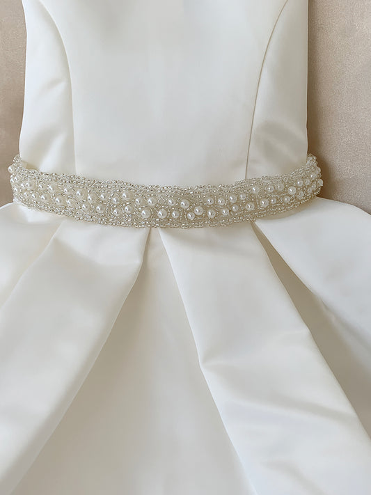 ivory dress with a decorative belt featuring pearls and crystals on a neutral background