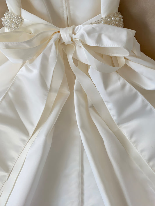 Close-up of a white dress with a large bow detail.