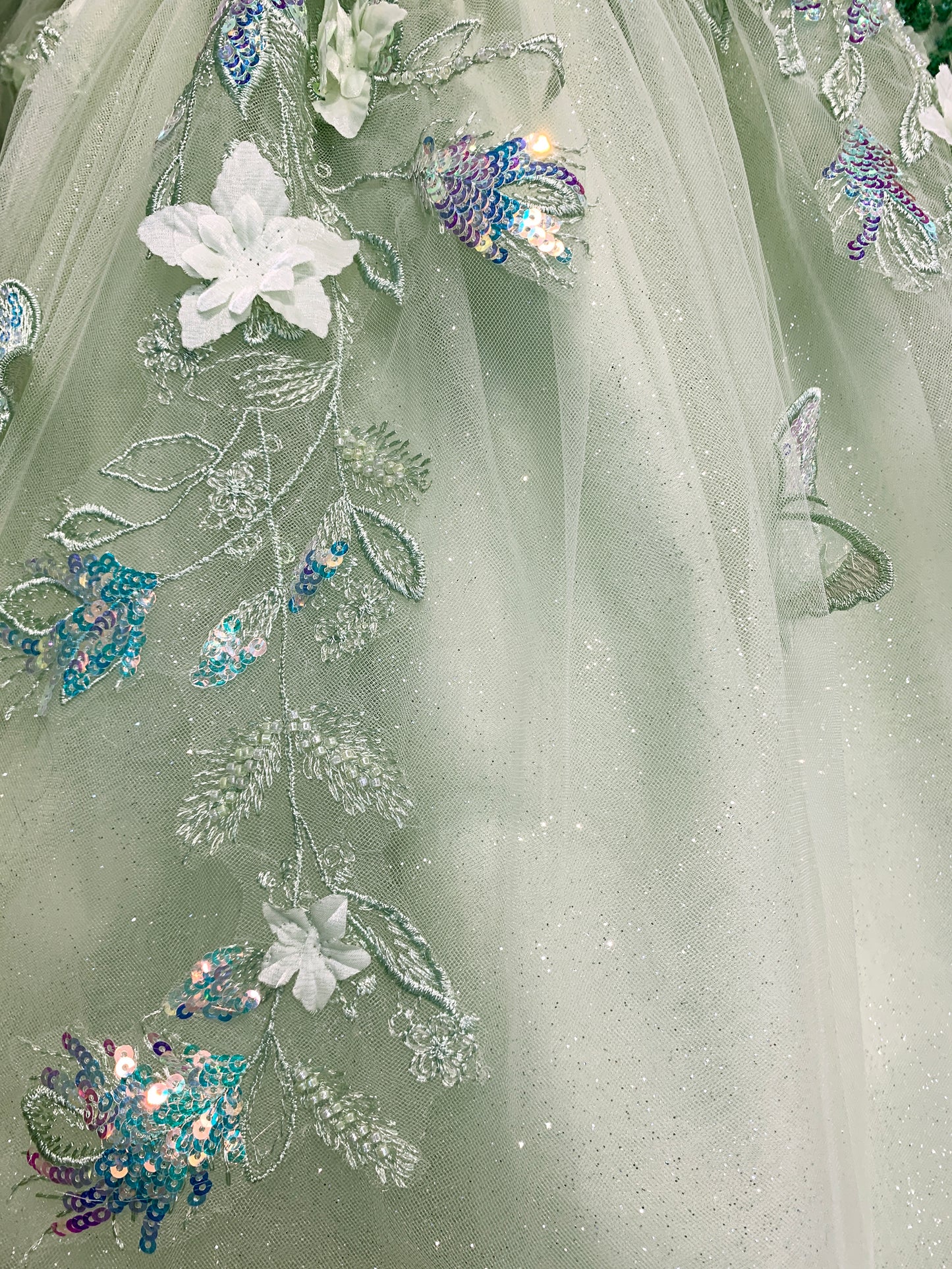 The mesh skirt serves as the base, embellished with floral, butterfly details, sequins, and delicate embroidery.