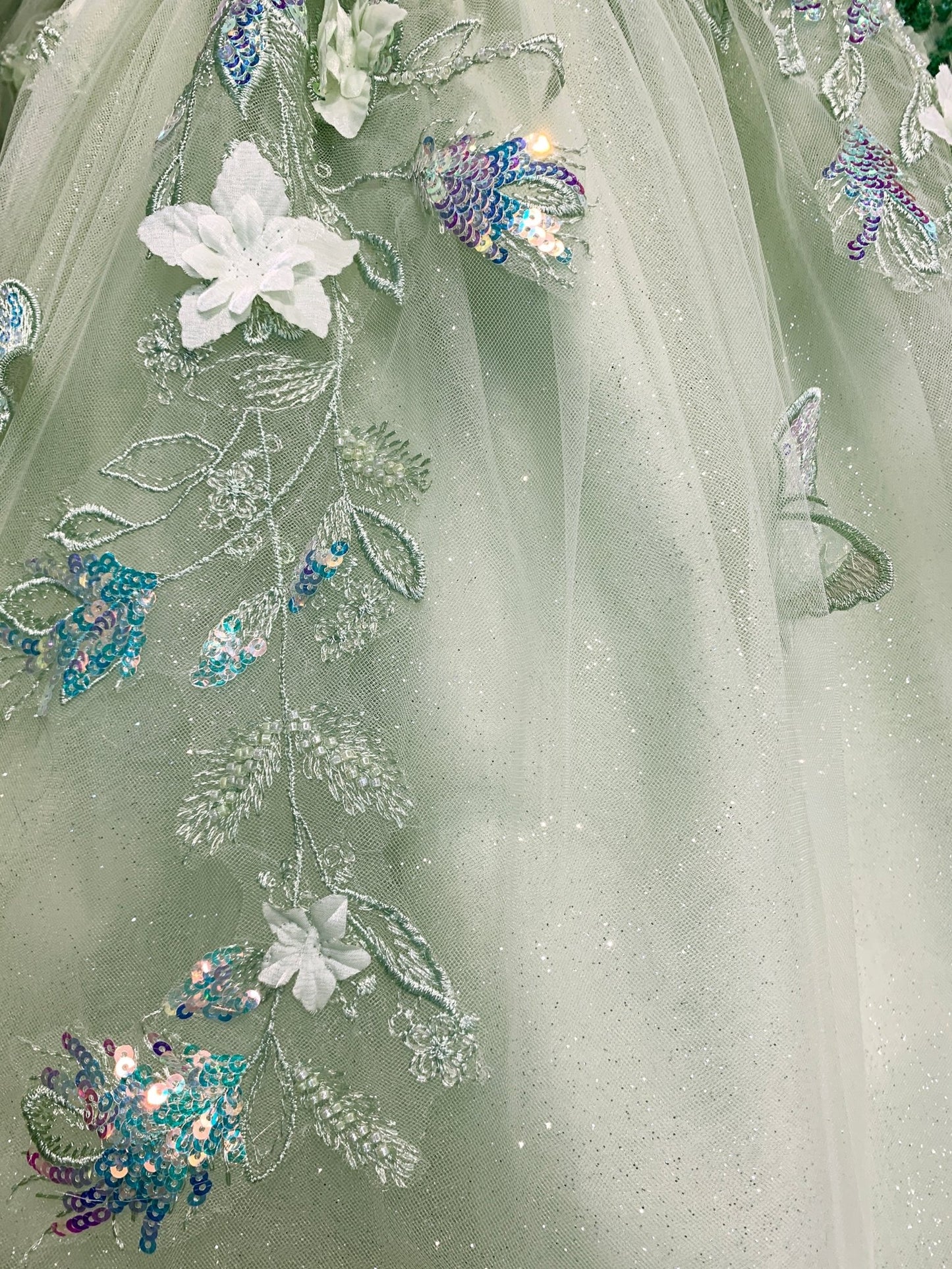 The mesh skirt serves as the base, embellished with floral, butterfly details, sequins, and delicate embroidery.