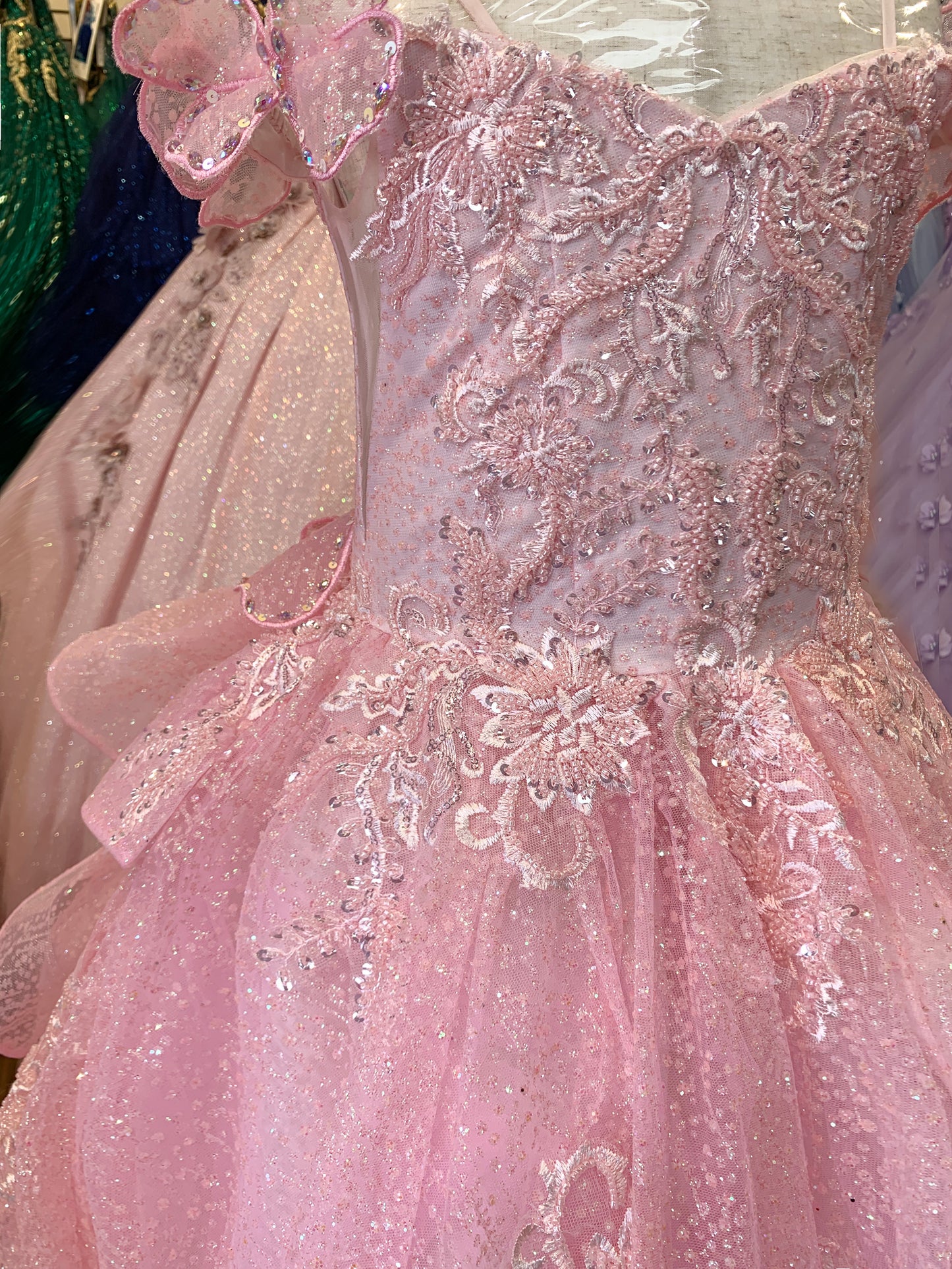 Close-up of a pink dress with intricate detailing and floral embellishments.