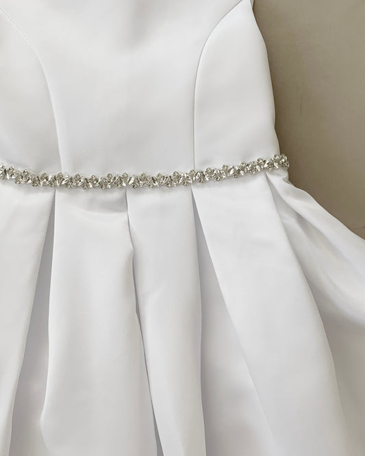 White dress with a silver belt on a neutral background