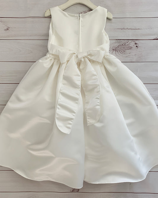 Ivory dress with a bow on a wooden surface
