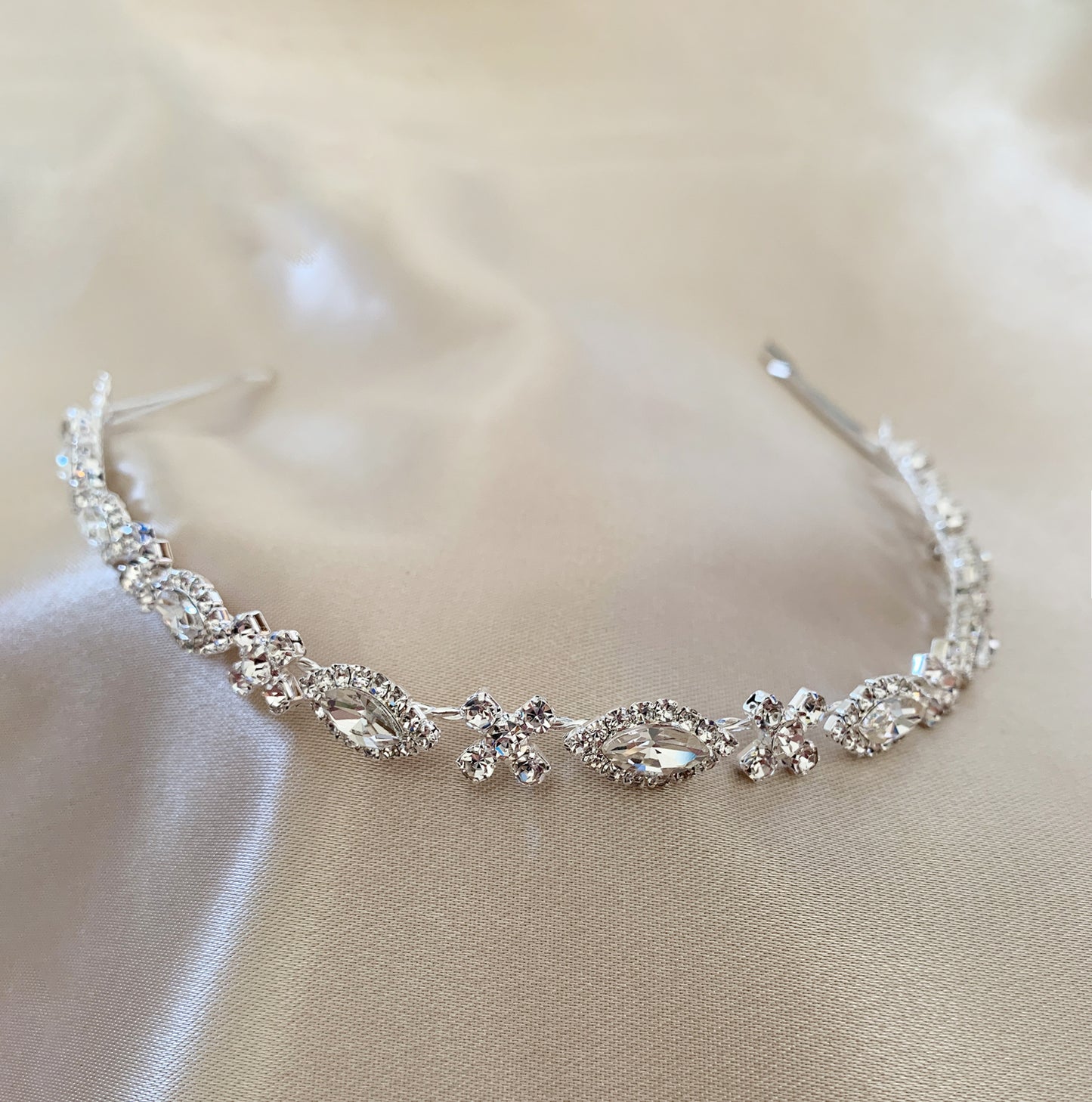 Silver tiara with clear stones on a beige fabric background