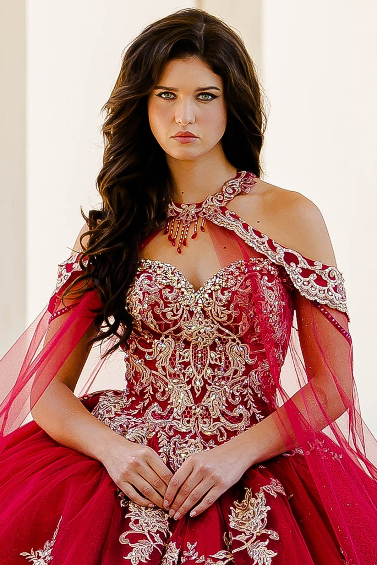 Bodice close-up highlights a wine quinceañera dress with gold embroidered lace, corset bodice and cape.