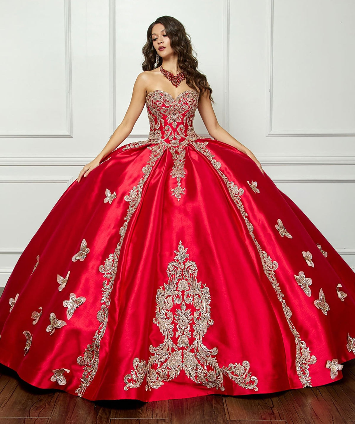 Front view presents a red quinceañera dress with gold butterfly applique, pouf arm cuffs and satin skirt.