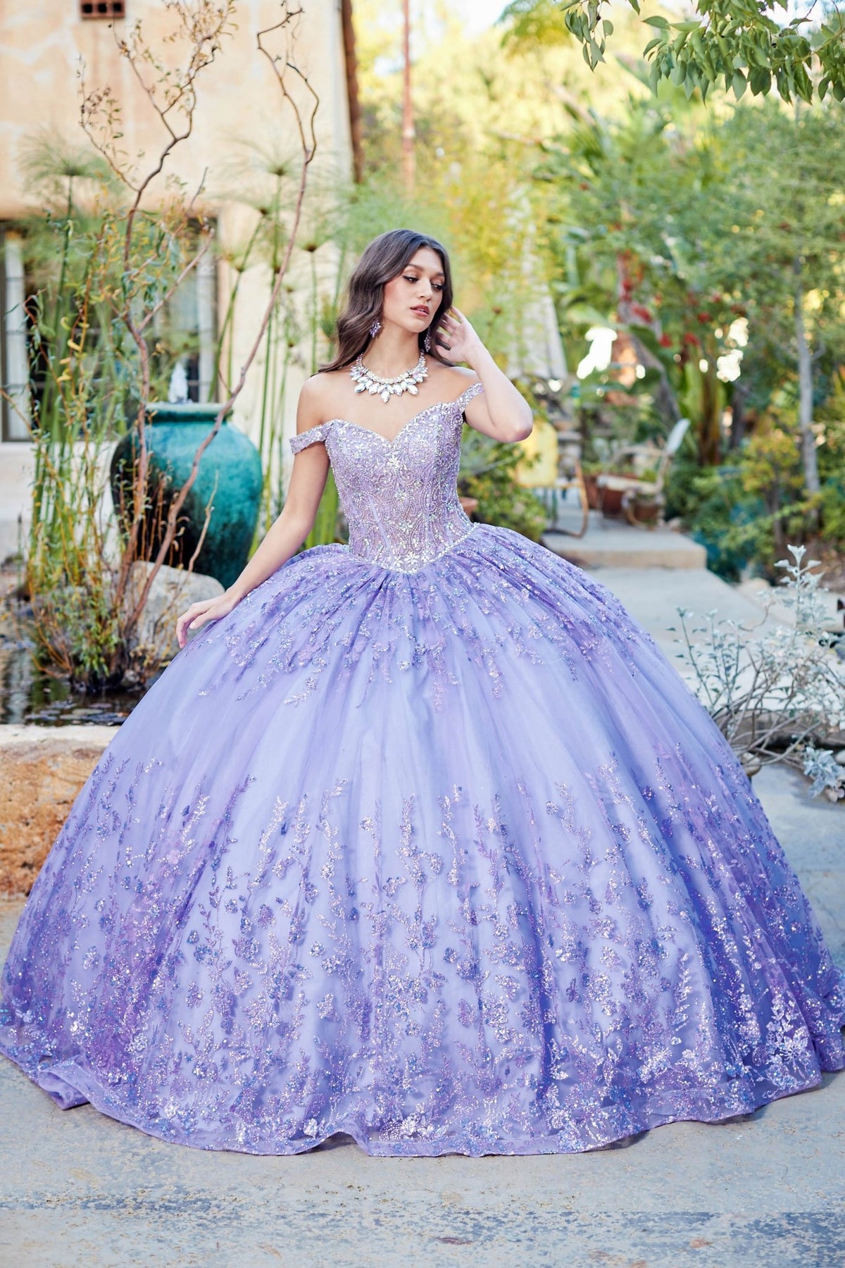 Detailed view highlights a lilac quinceañera ball gown with see-through corset bodice, gemstone details and no sleeves.