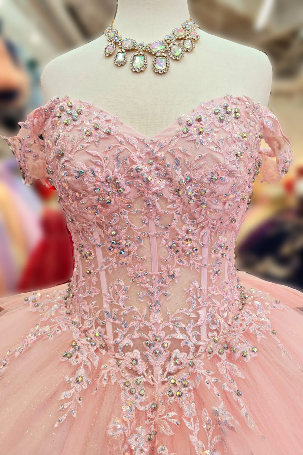 Detailed view highlights baby pink quinceañera ball gown with sparkling rhinestones bodice, off-shoulder neckline.