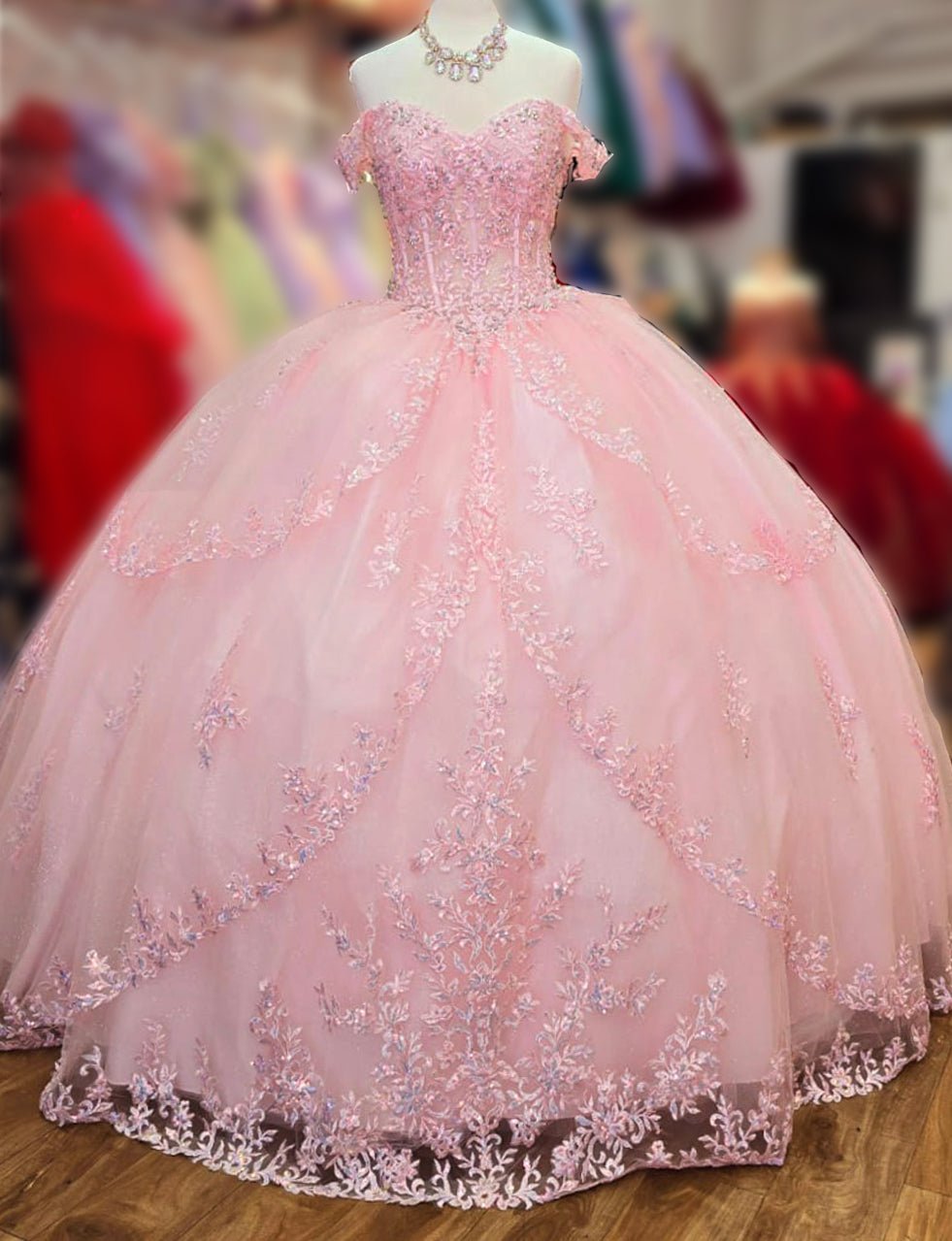 Intricate features stand out across full a baby pink quinceañera ball gown with rhinestones bodice, off-shoulder neckline.