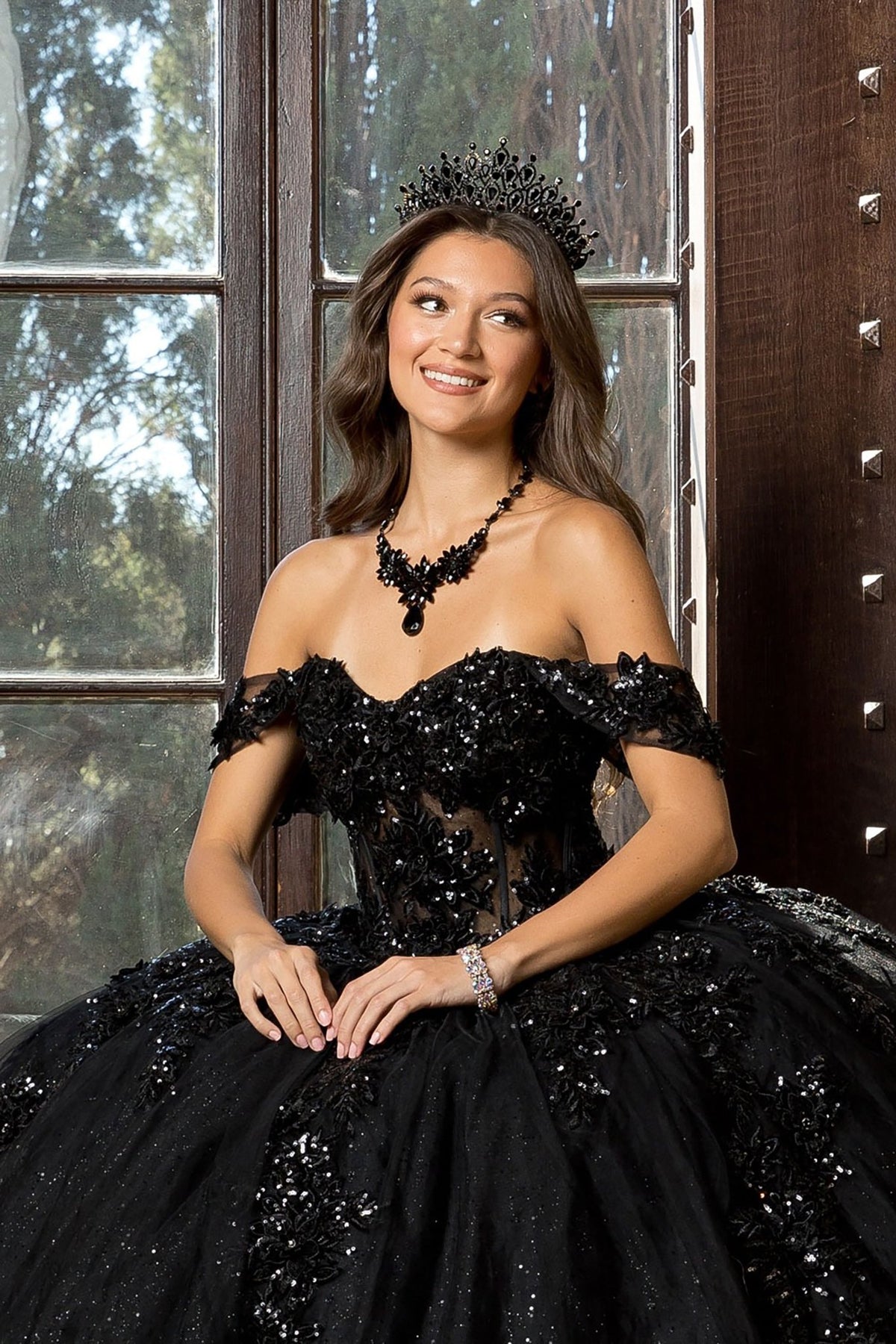 Close-up view reveals a black quinceañera ball gown with detachable sleeves, 3D flowers, glitter embellishments and corset bodice.