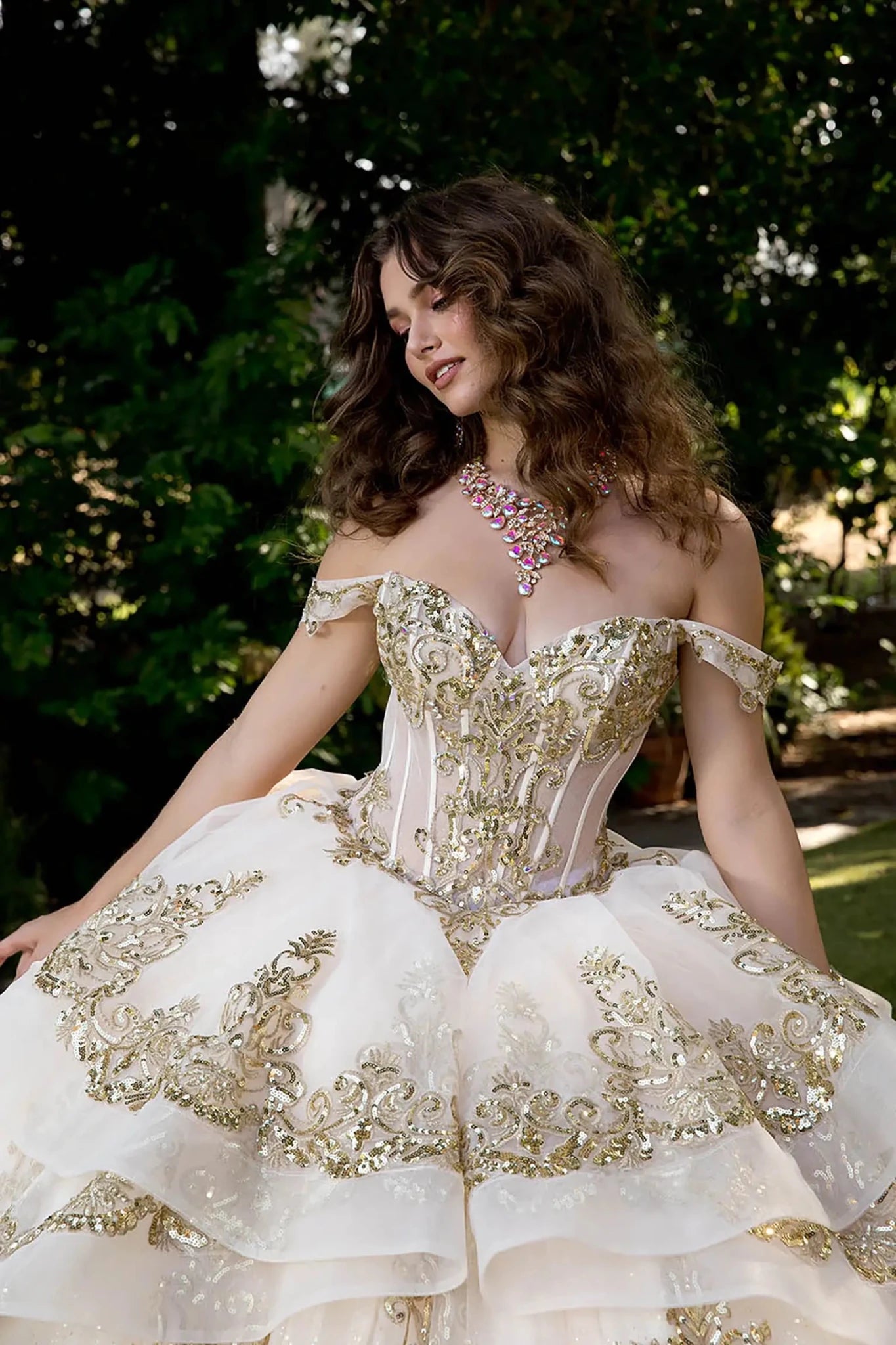 Model wearing ivory glitter tulle ball gown with sweetheart neckline and gold embellished corset.
