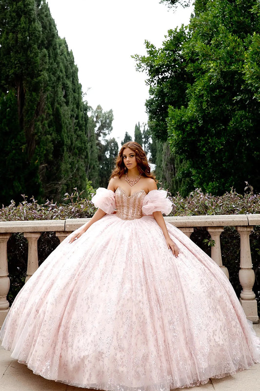 Woman in a pink ball gown standing outdoors with greenery in the background