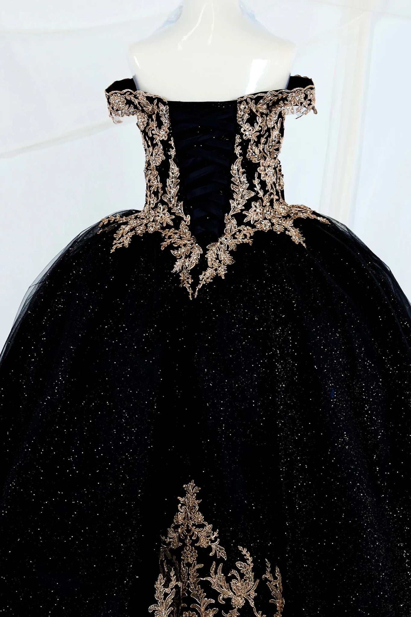 Black shiny tulle mini quince ball gown with gold embroidery showing the back of the dress, lace up back