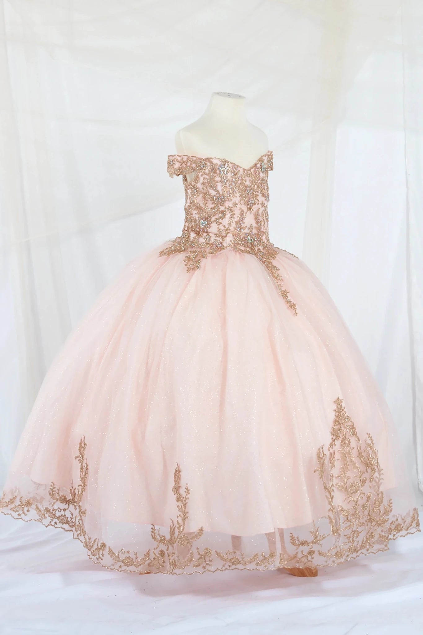 Pink off the shoulder kid ball gown mini quince dress with gold embroidery on a mannequin against a white background
