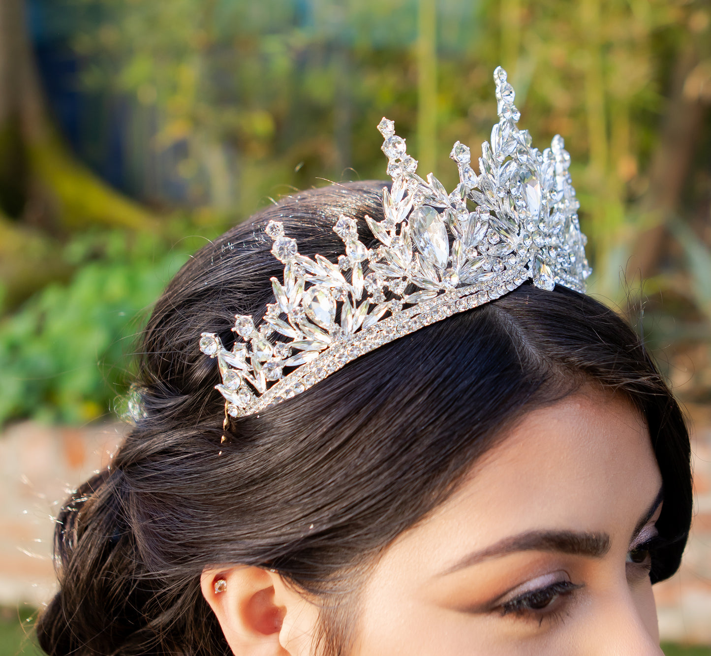 Person wearing a sparkling tiara with a blurred natural background