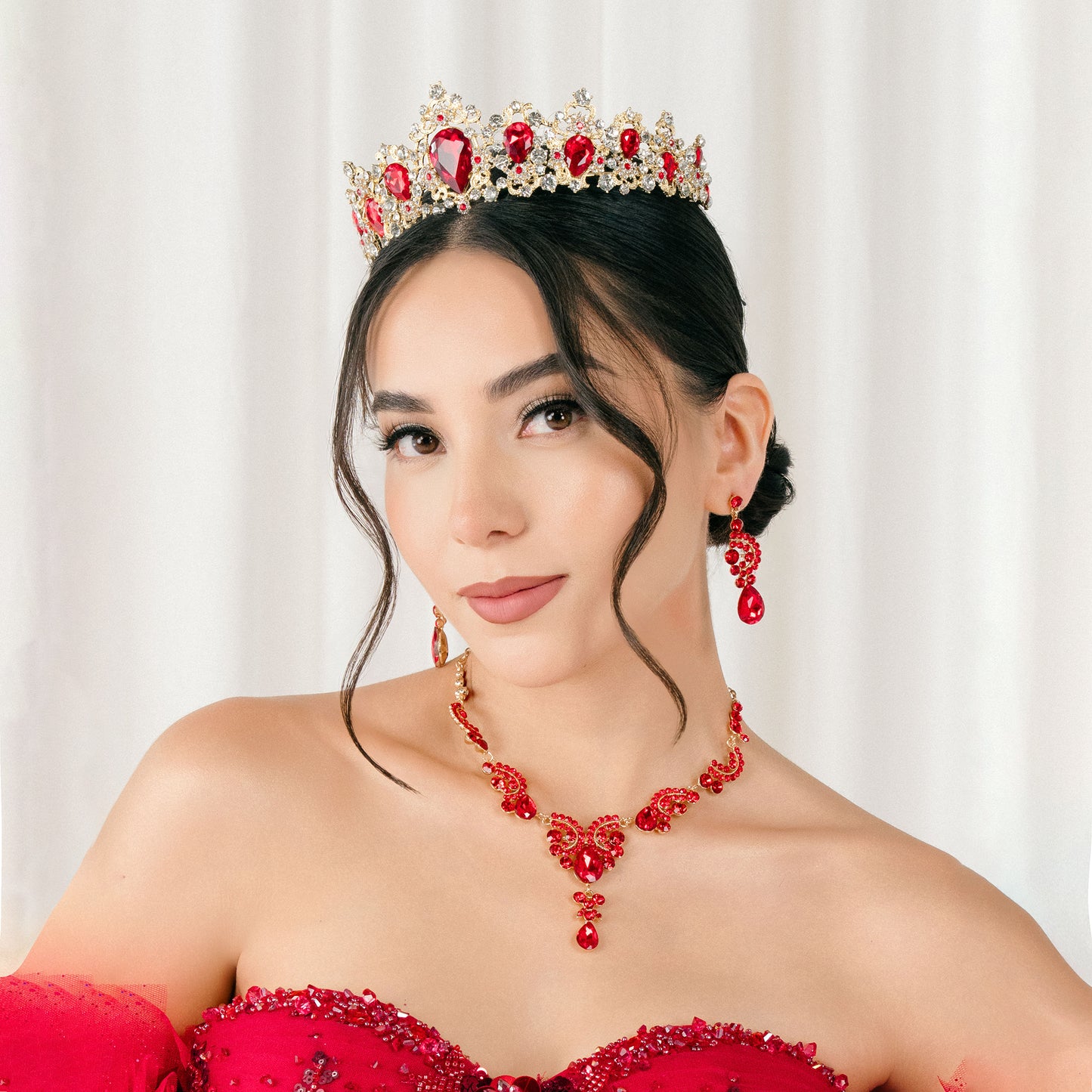 Woman wearing a red beaded tiara and necklace with a white background