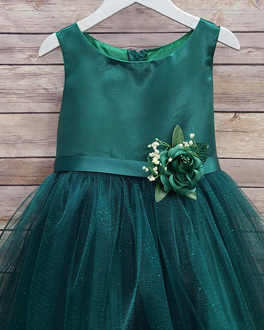 Green dress with floral embellishment on a wooden surface