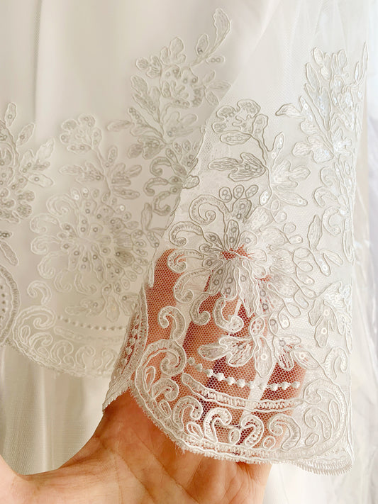 Close-up of a hand holding a white lace sleeve.
