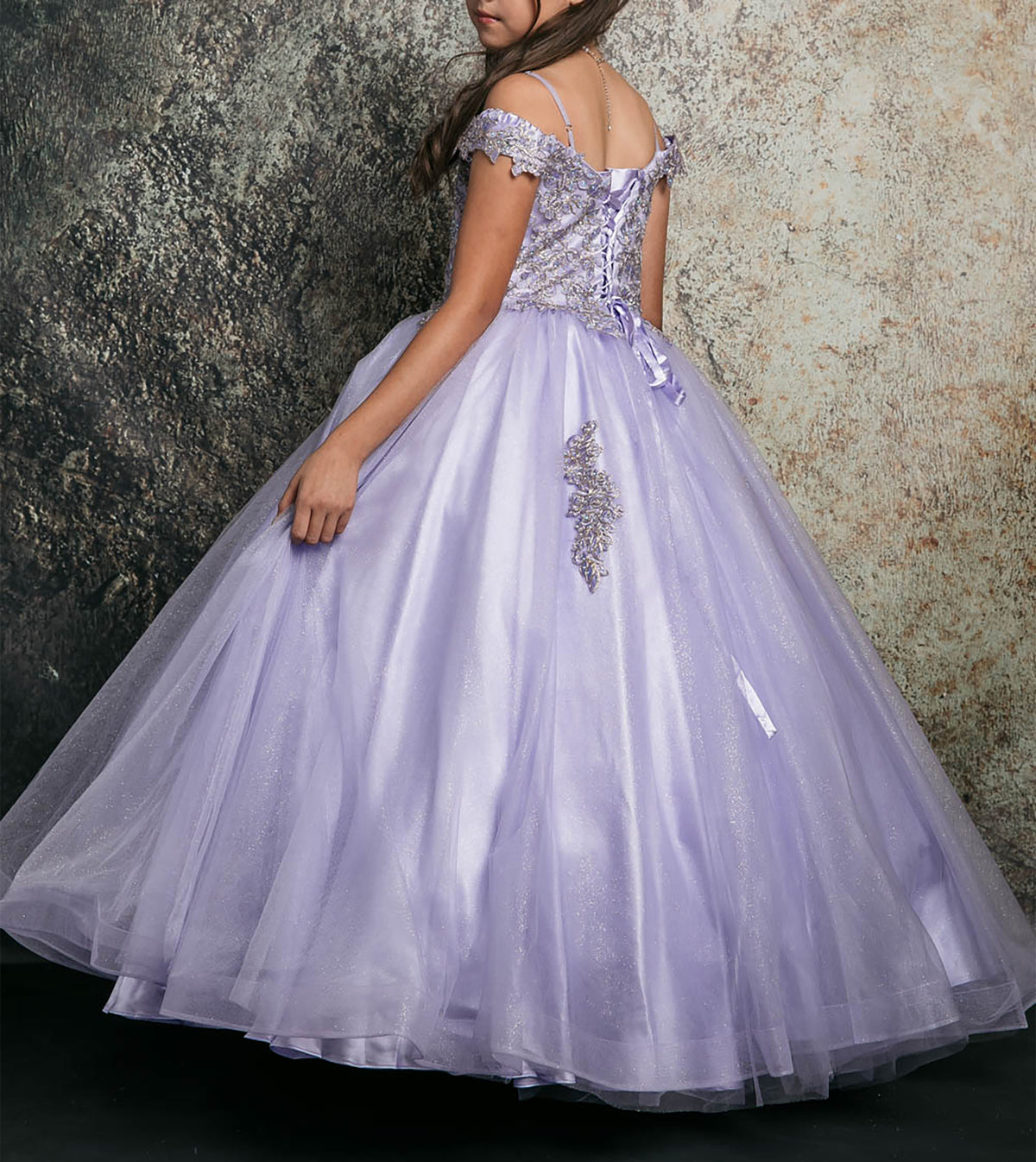 Back detail shows lilac kids mini quince dress with lace-up corset bodice, floral appliques, and layered tulle skirt.