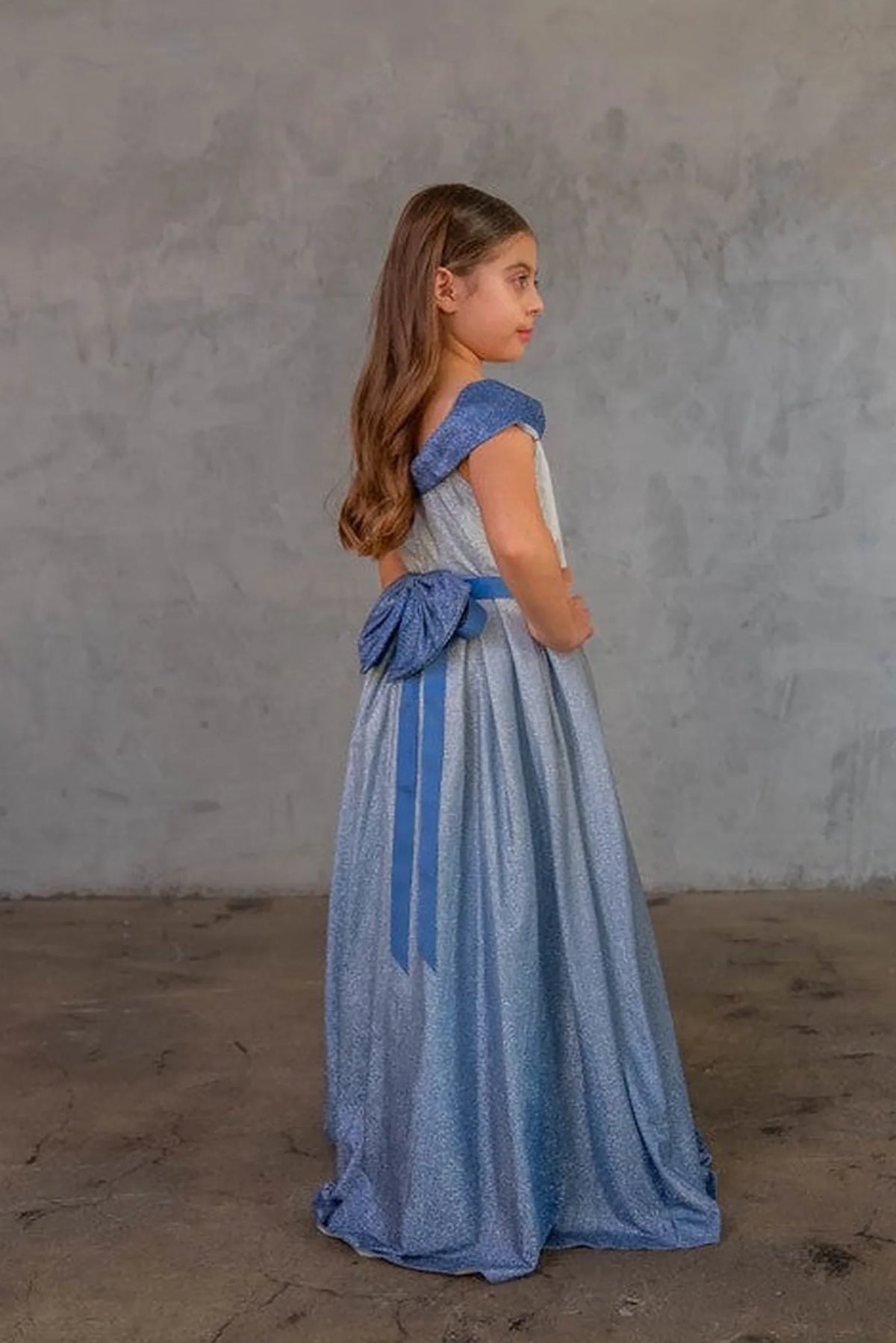 A closer crop highlights off-the-shoulder neckline with an oversized back bow on the Blue/Silver mini quince dress.