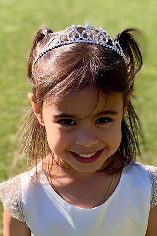 Young girl wearing a tiara with a blurred green background