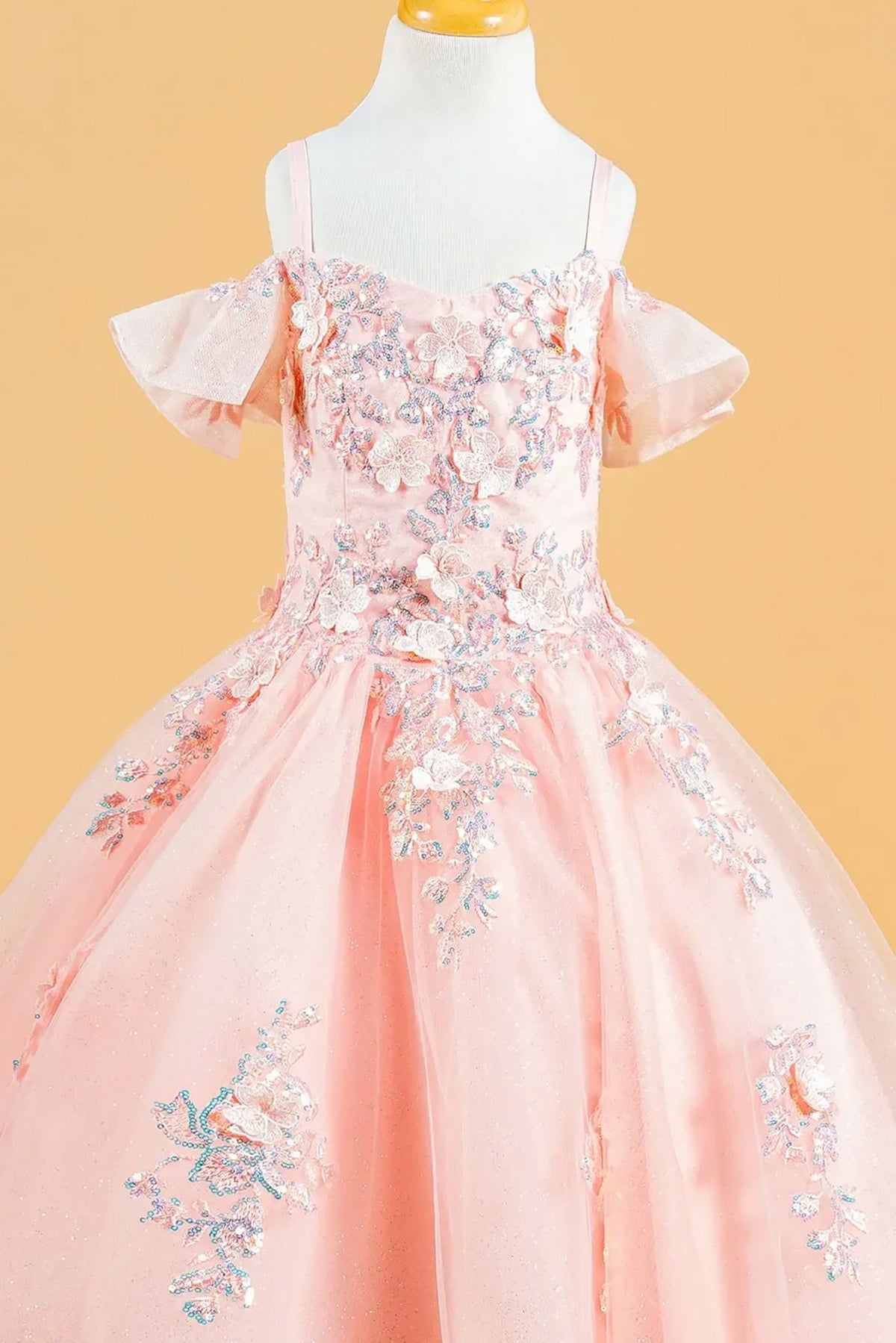 Detailed view highlights a blush kids cold shoulder mini quince dress highlighting 3D flowers, sequins, and lace-up back.