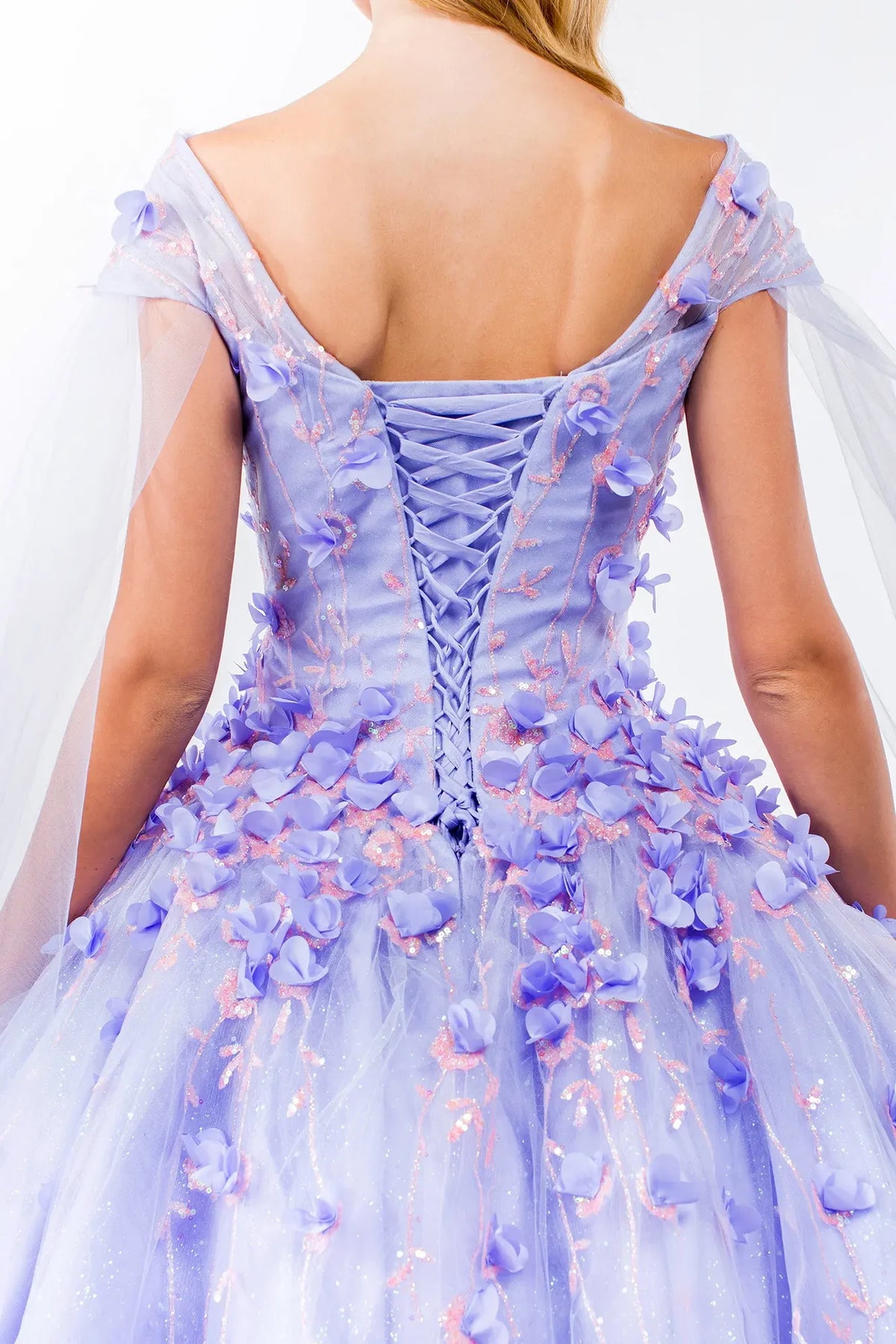 Layered skirt showcases the Lilac quinceañera ball gown with detachable cape sleeves.