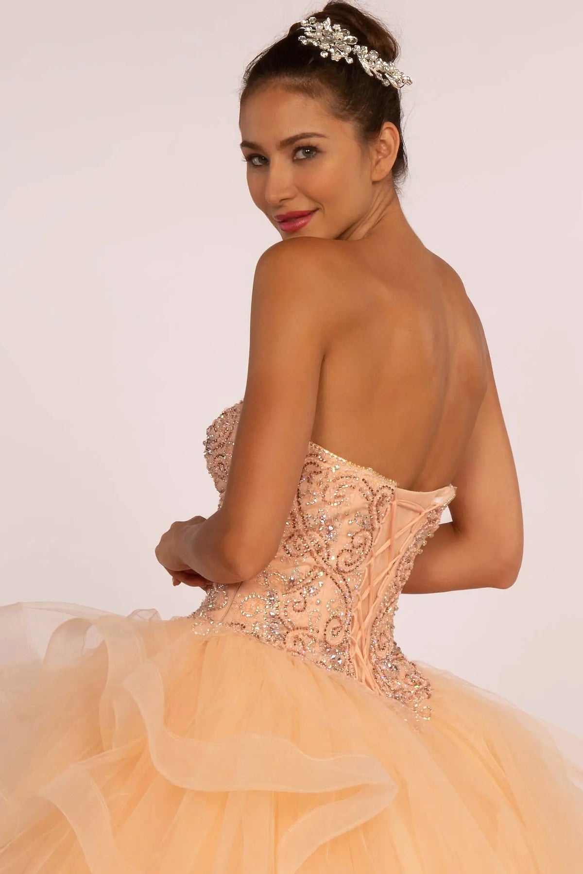 Embroidered details frame the Peach quinceañera ball gown with rhinestone bodice.