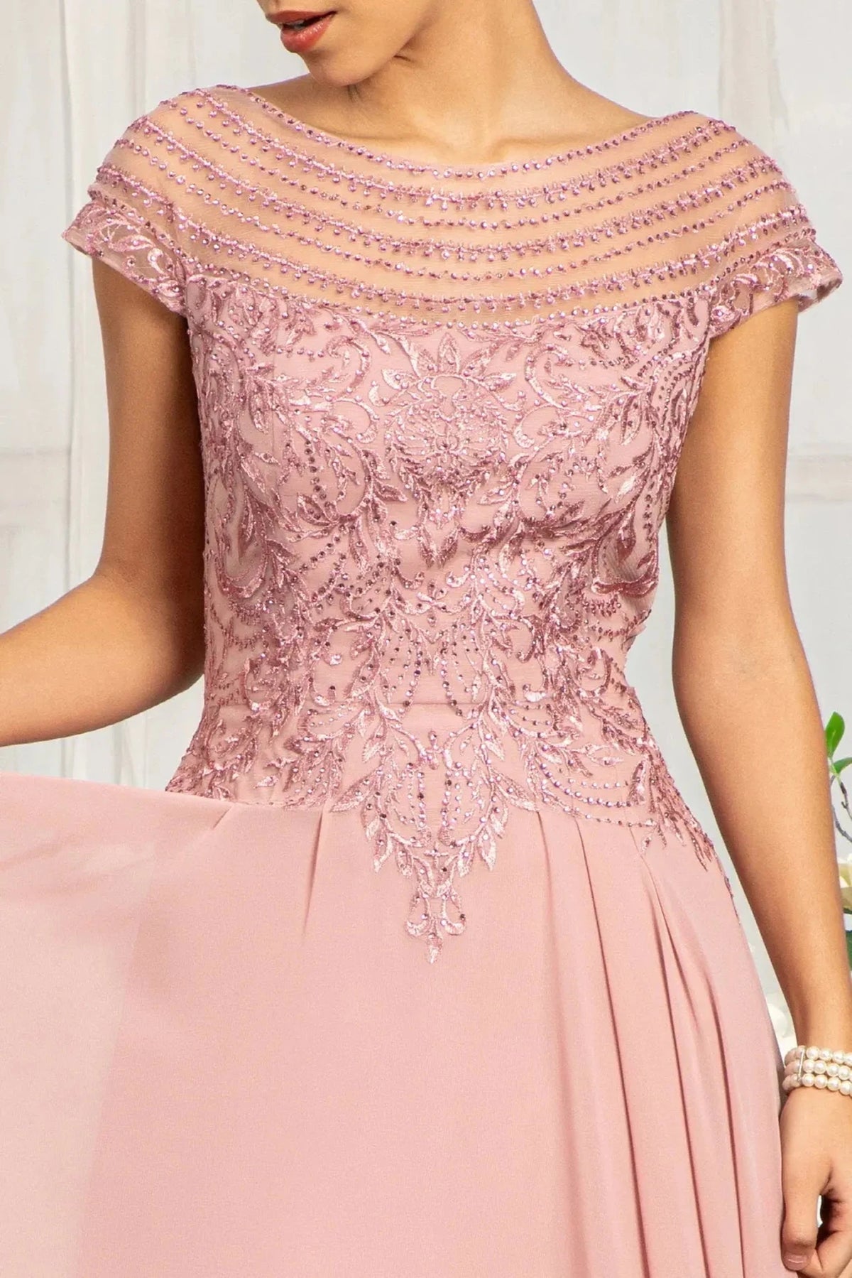 Bodice close-up highlights dusty Rose mother of the bride dress featuring boat-neck bodice with cap sleeve and beads, embroidery.