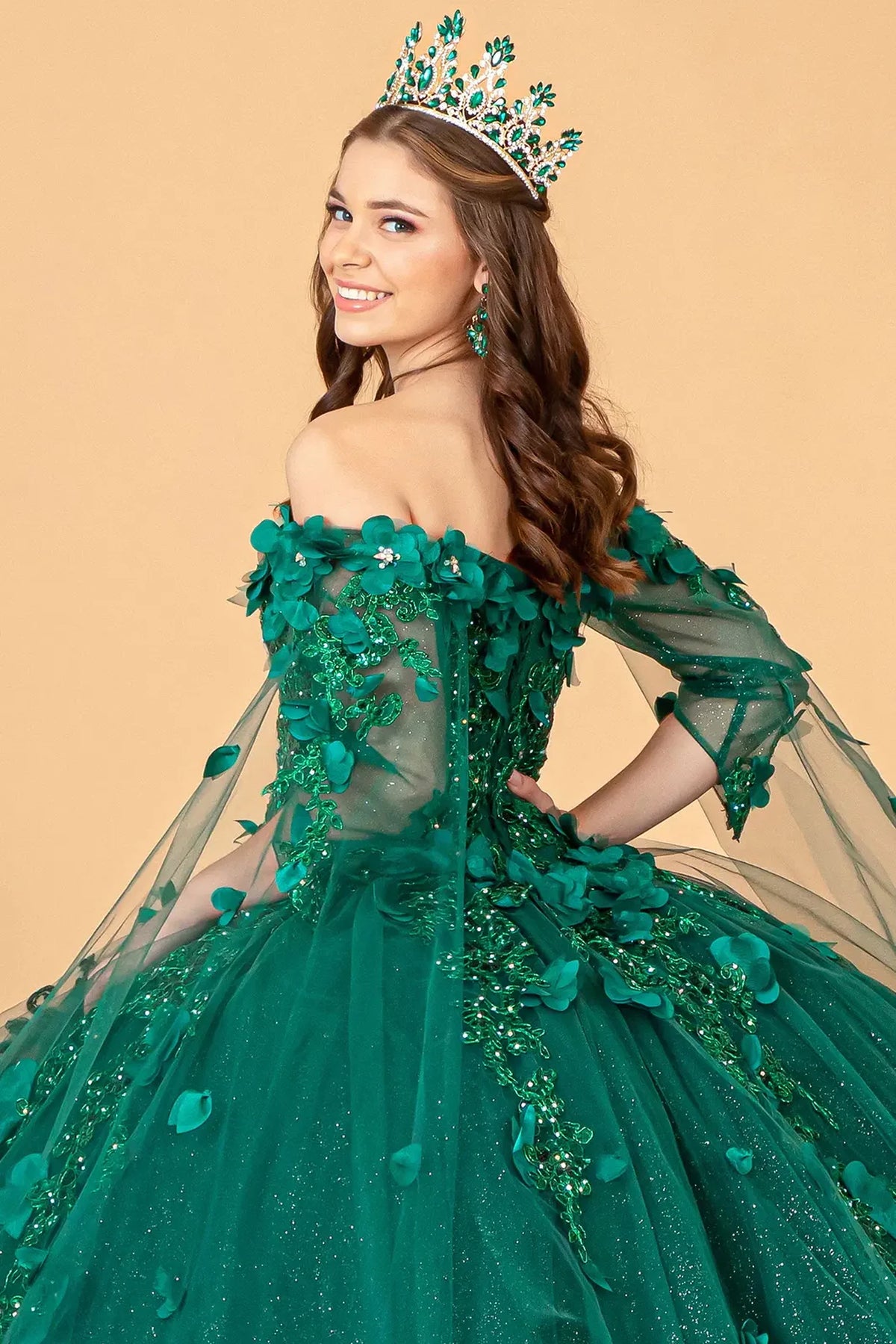 Layered skirt showcases the Green quinceañera ball gown with shoulder mesh drapes.