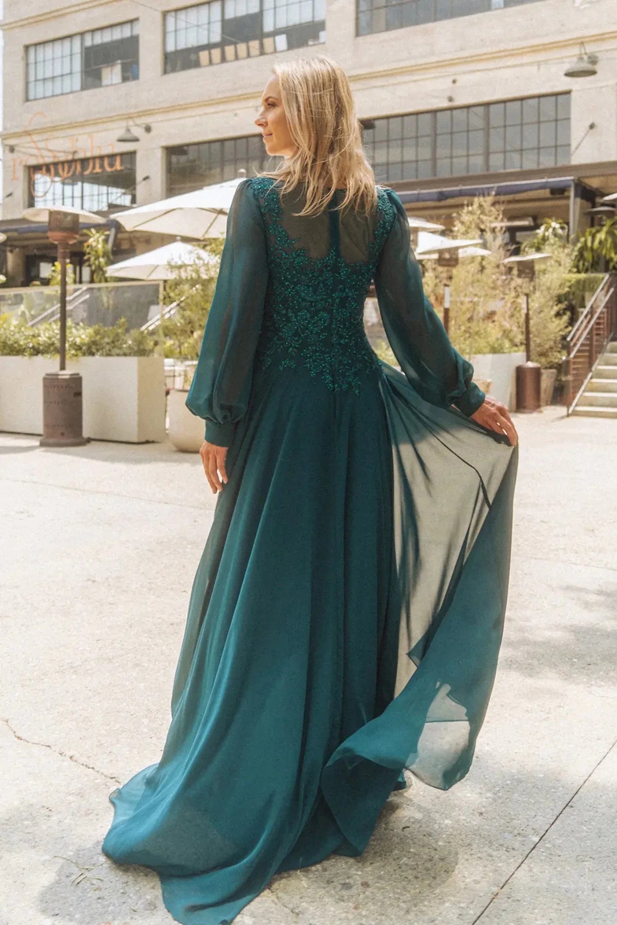 Rear view reveals teal a-line mother of the bride dress with concealed zipper back and long sleeve.