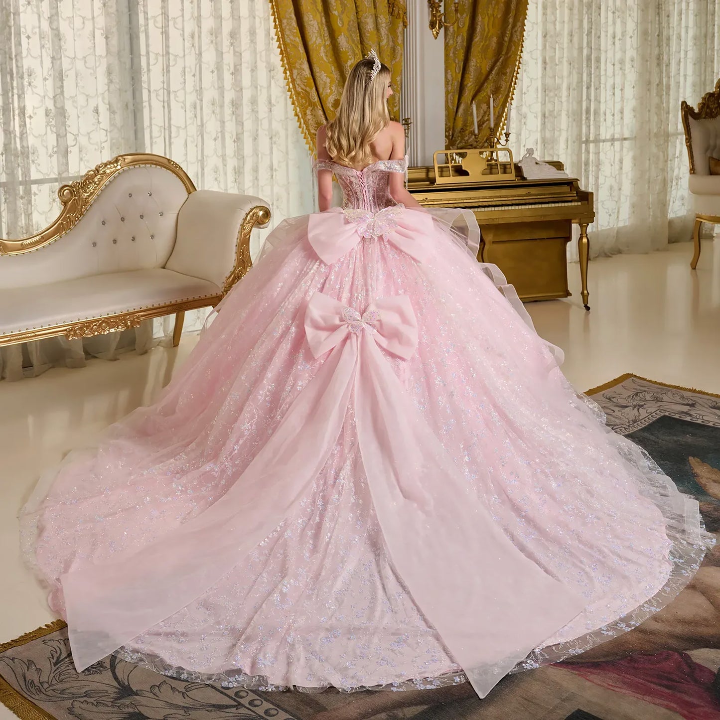Woman in a pink gown standing in an opulent room with gold decor back view