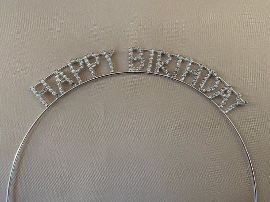 Silver 'Happy Birthday' headband on a beige background