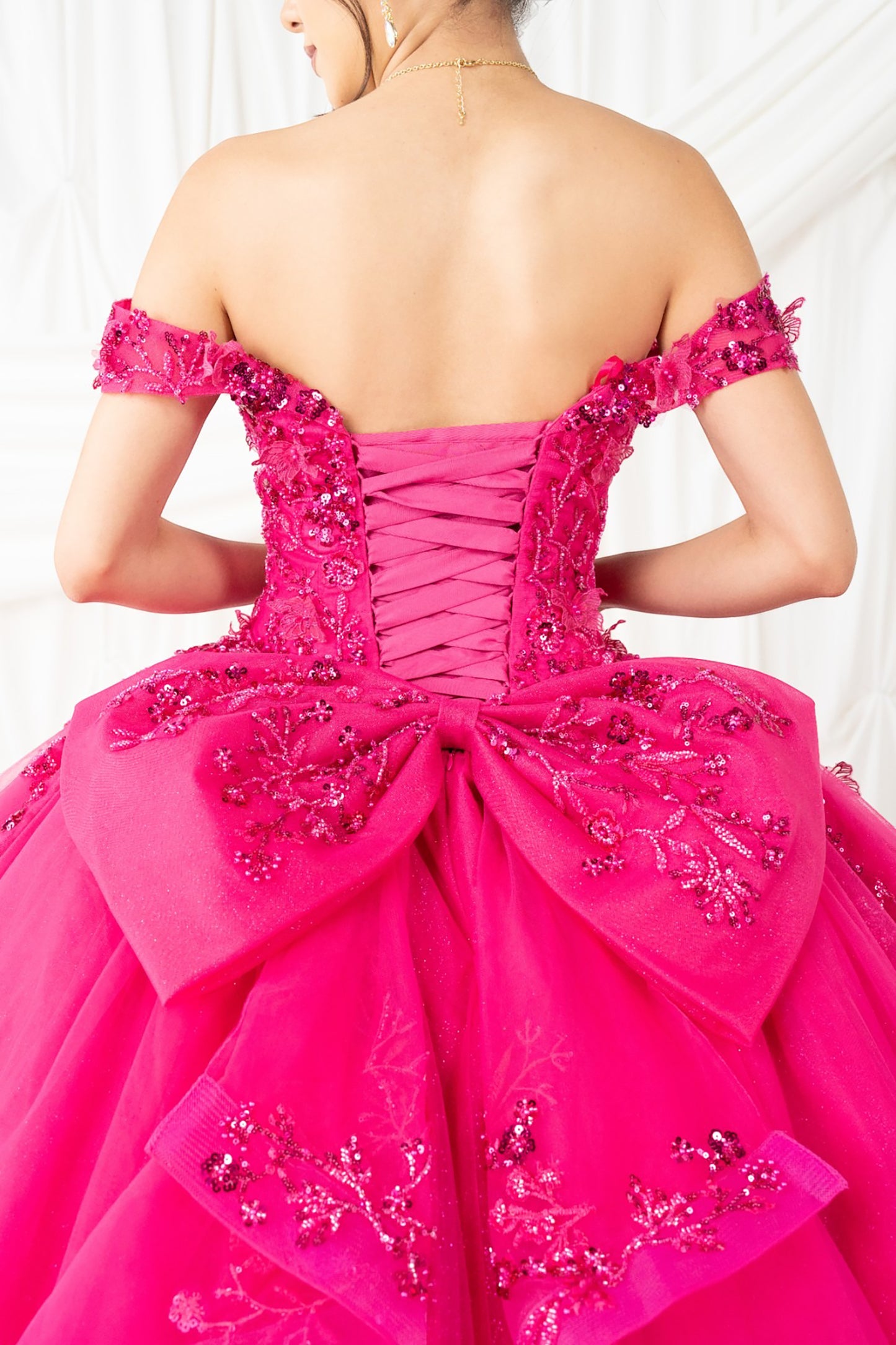 fuchsia off-shoulder gown with intricate detailing on a white background