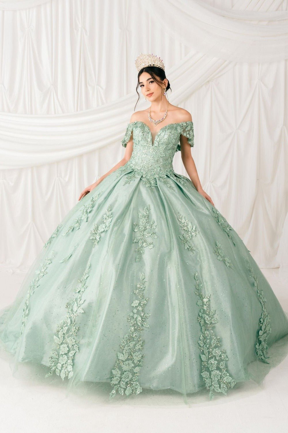 Full-length view highlights sage quinceanera ball gown with floral sequin appliques, glitter lace train, and voluminous skirt.