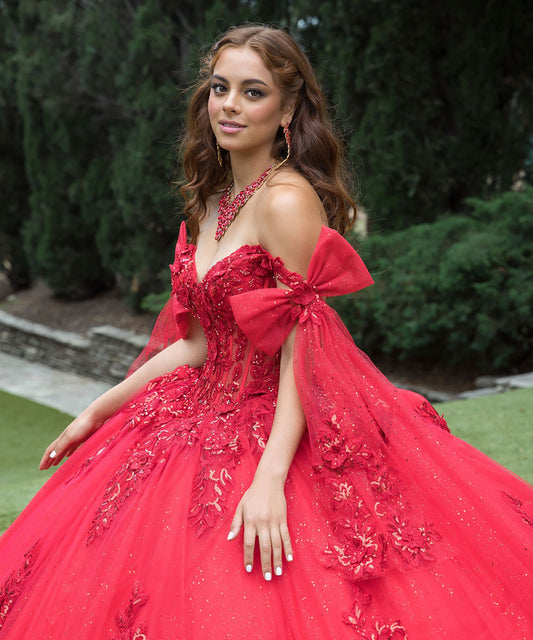 Woman in a red formal gown with floral details outdoors.