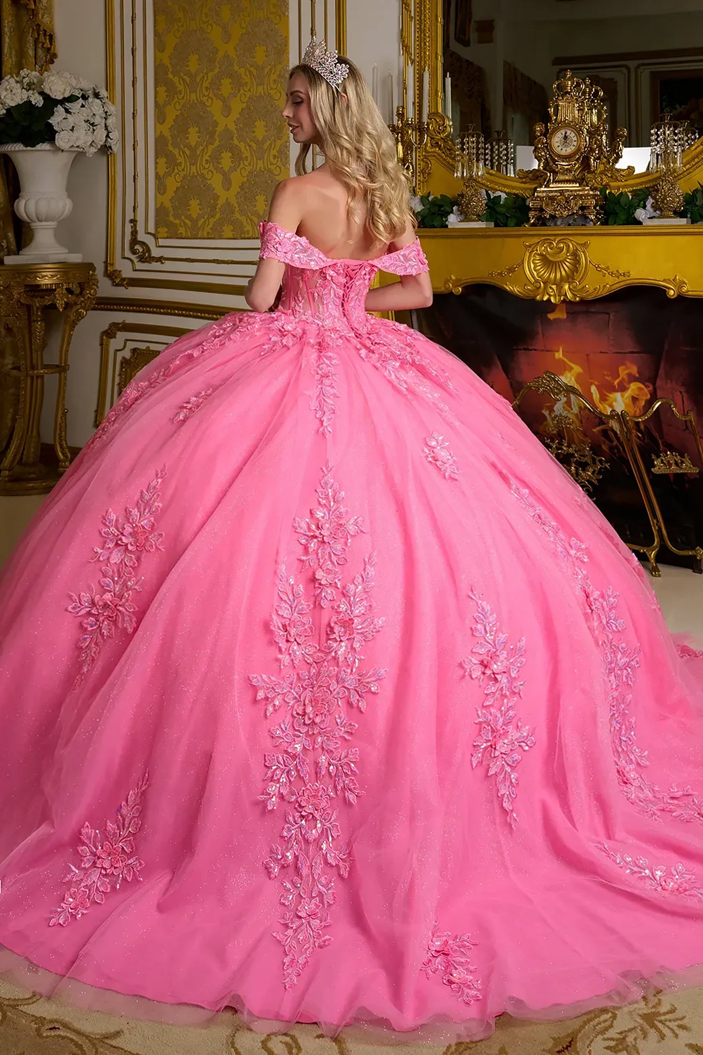 Woman in a pink ball gown standing in an ornate room.
