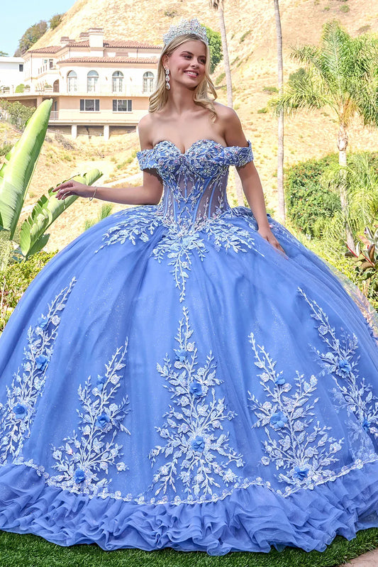 Woman in a dusty blue quince embroidered ball gown standing outdoors with greenery and a house in the background.