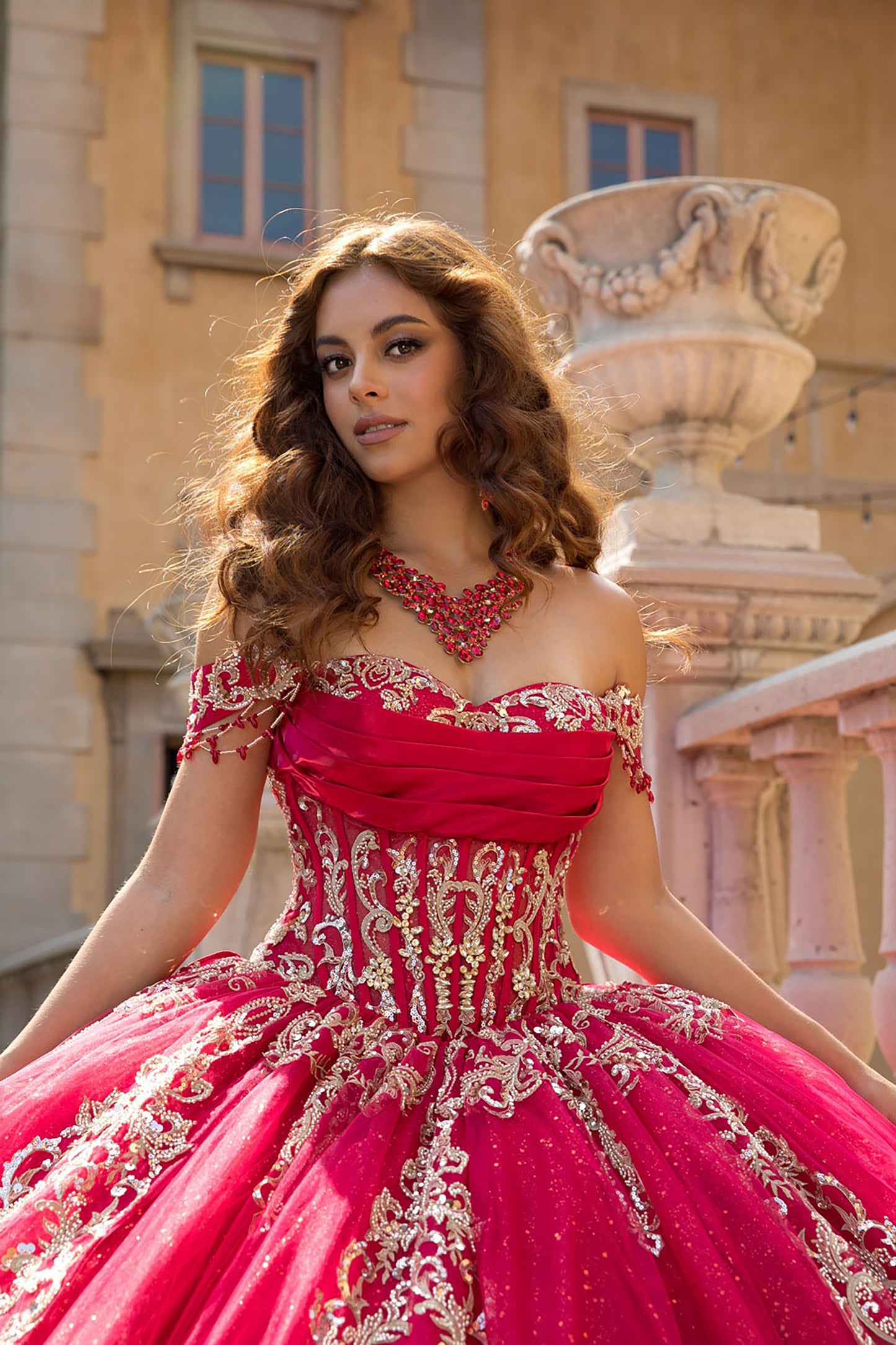 Woman in a red and gold dress standing in front of classical architecture