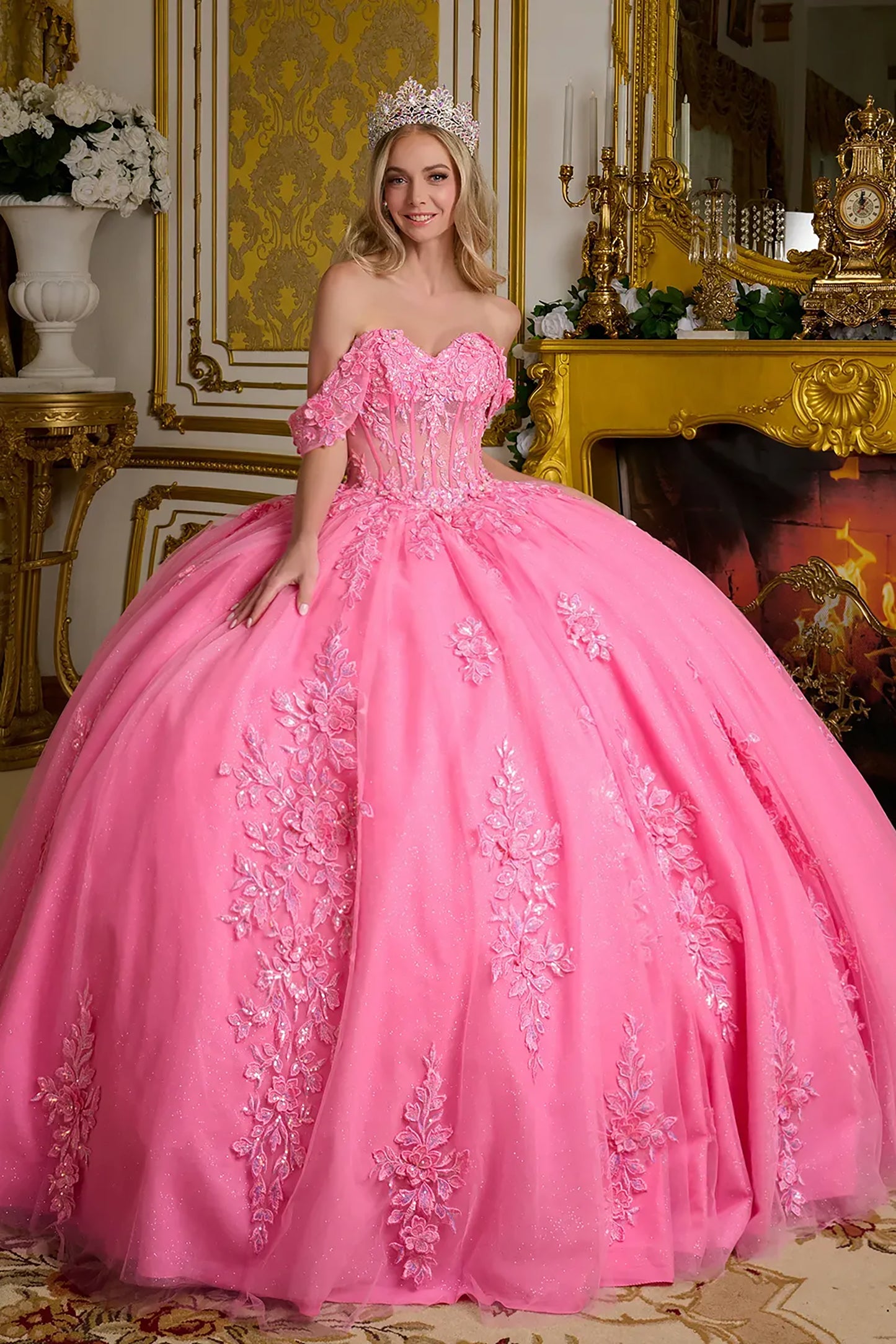 Woman in a pink ball gown with floral embroidery in an ornate room.