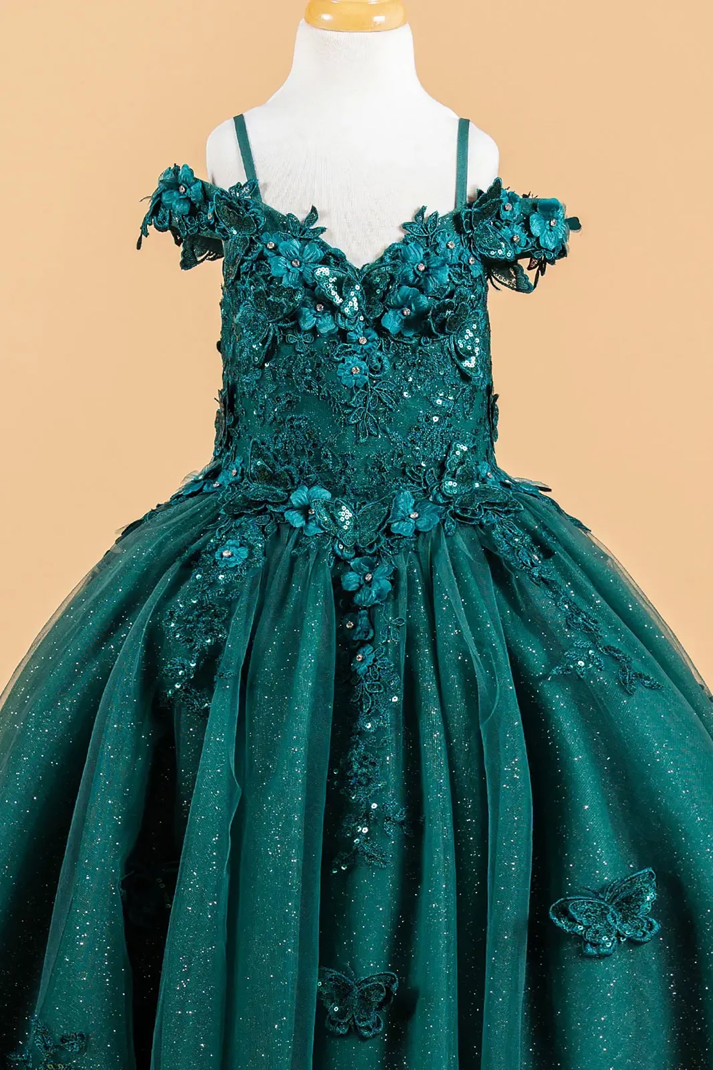Green evening gown with floral and butterfly details on a beige background