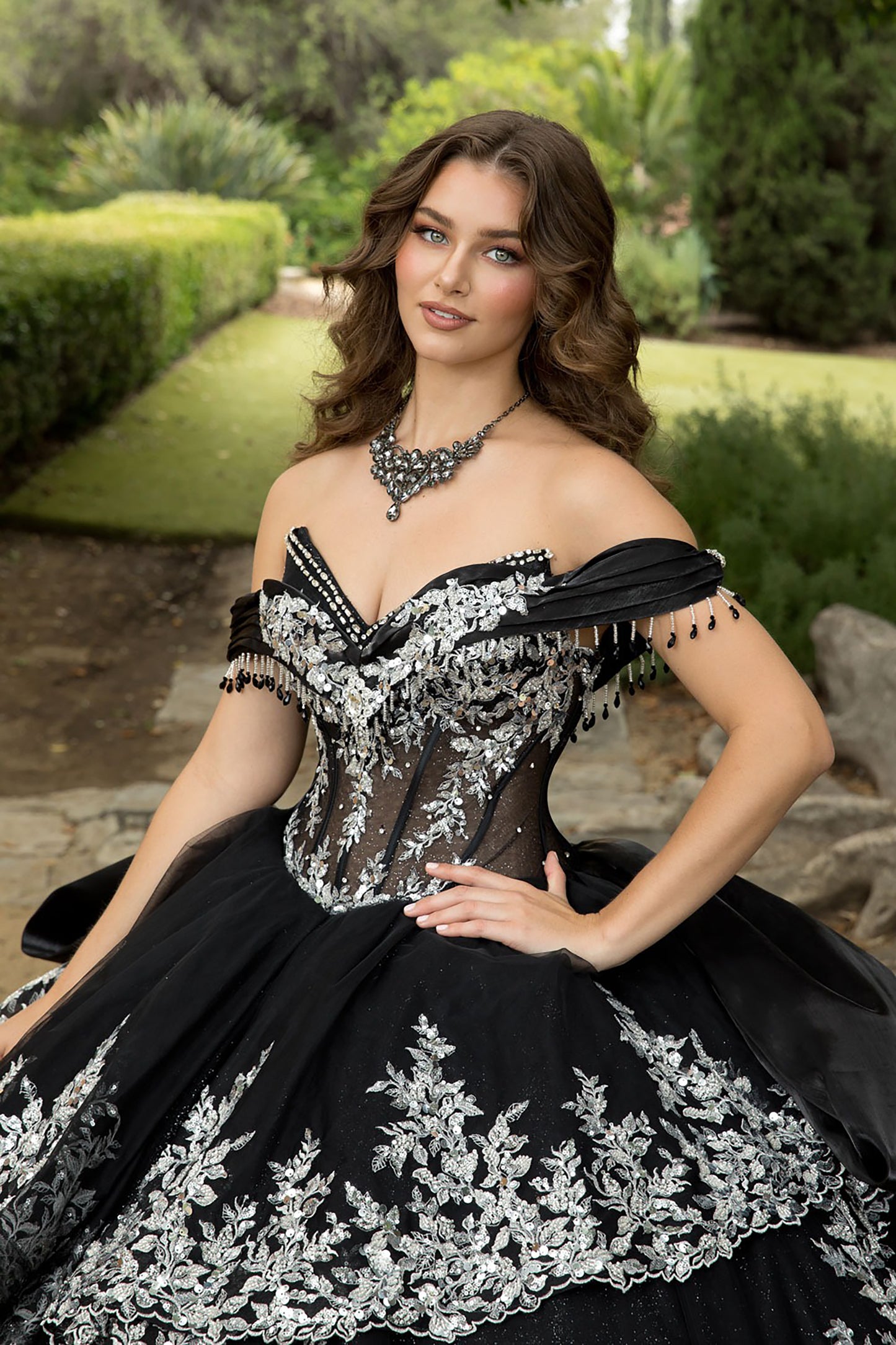 Woman in a black and silver formal gown sitting outdoors.