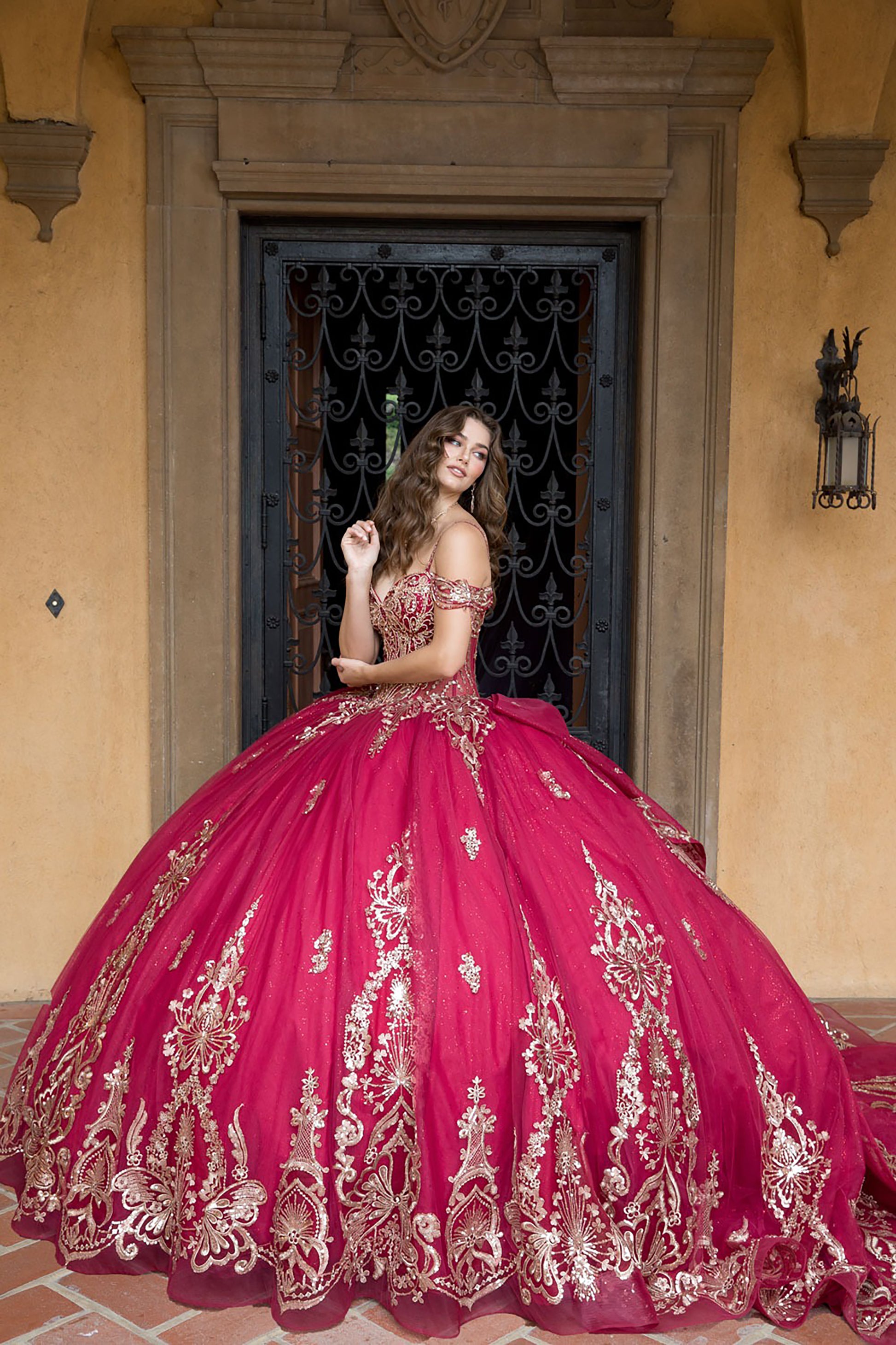 Woman in a red and gold embroidered dress standing in front of a decorative door.