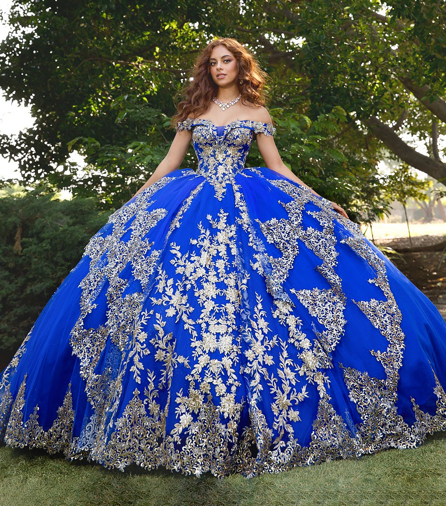 Woman wearing a blue and silver ball gown with floral patterns outdoors.