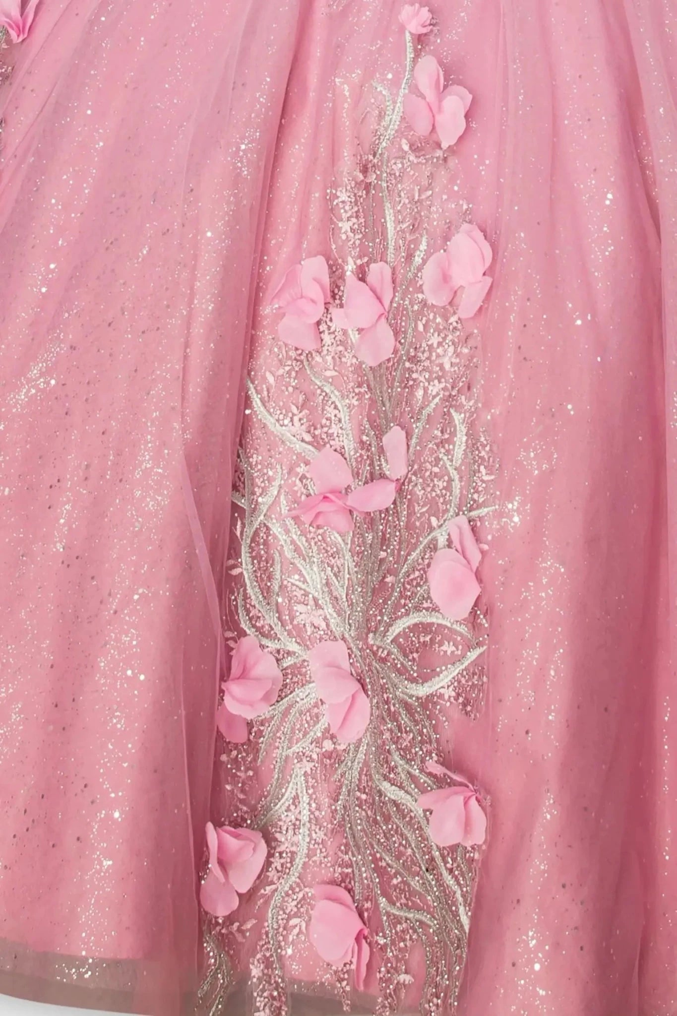 Close-up of a woman wearing rose quinceanera dress with floral embroidery, sequins, and rhinestone detailing