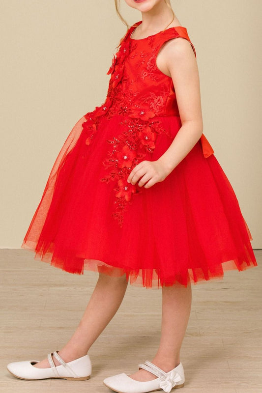 Young girl standing side-facing in red sleeveless flower girl dress with 3D floral appliqué detailing and voluminous wired tulle skirt