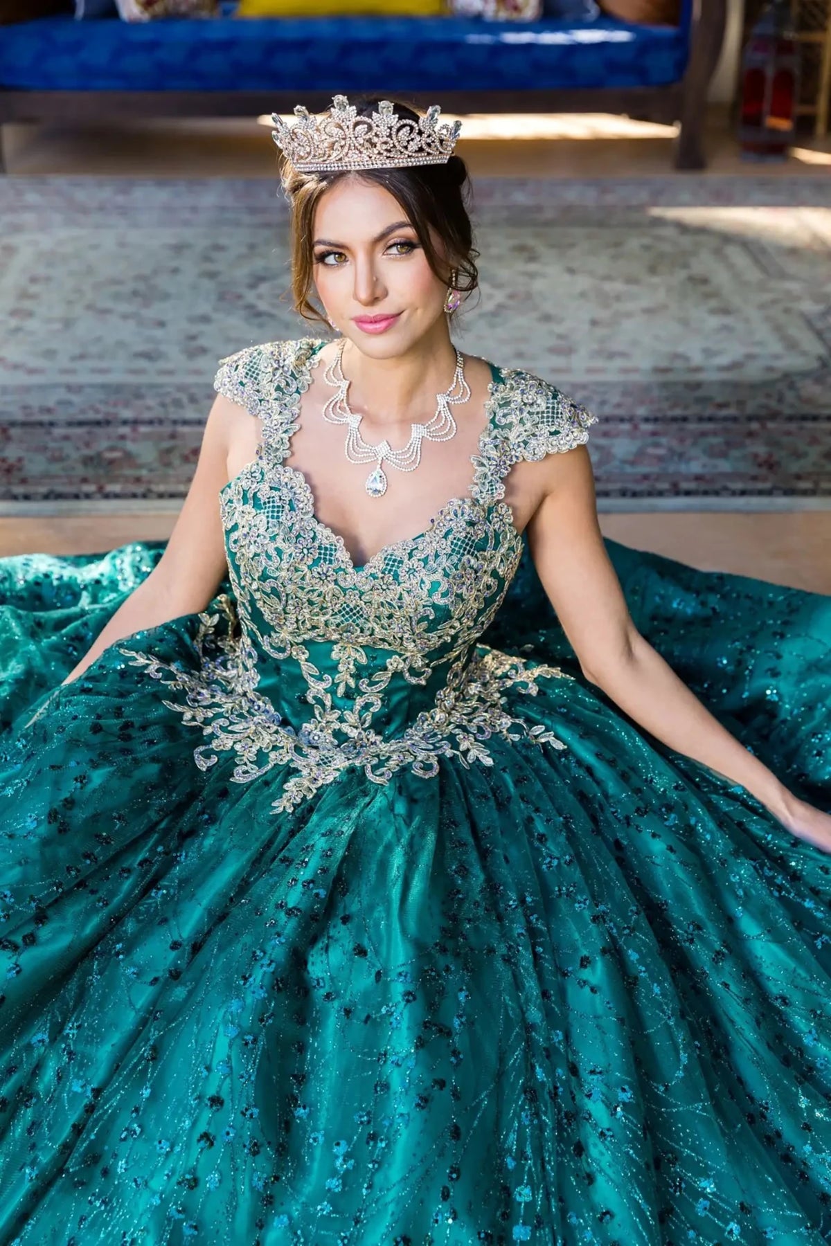 Front view presents hunter green quinceanera dress with gold embroidery, glitter tulle, satin fabric, and tiara detail.