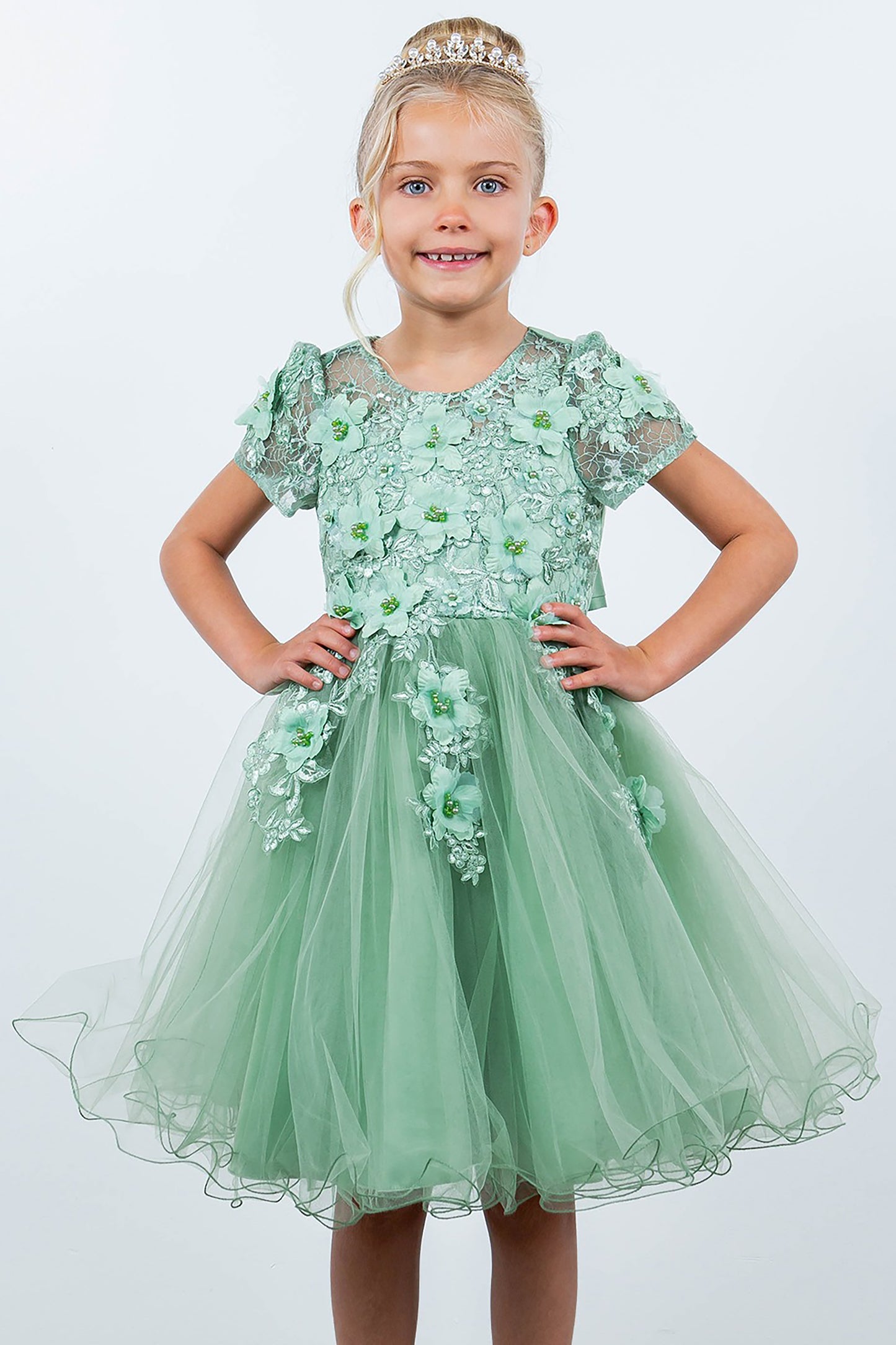 Young girl wearing a Sage floral dress with a tiara on a white background