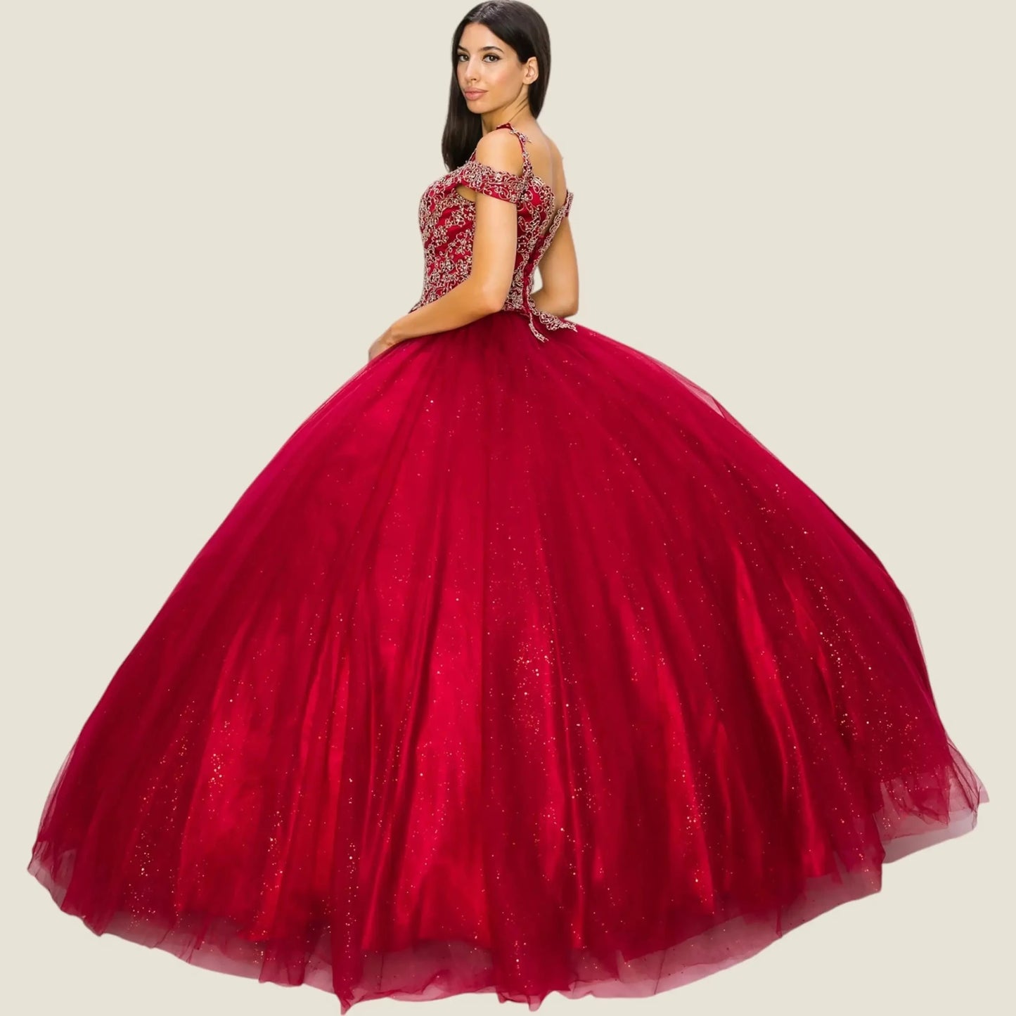 Side view of a woman wearing burgundy quinceanera ball gown with lace bodice, gold detailing, and glitter tulle fabric